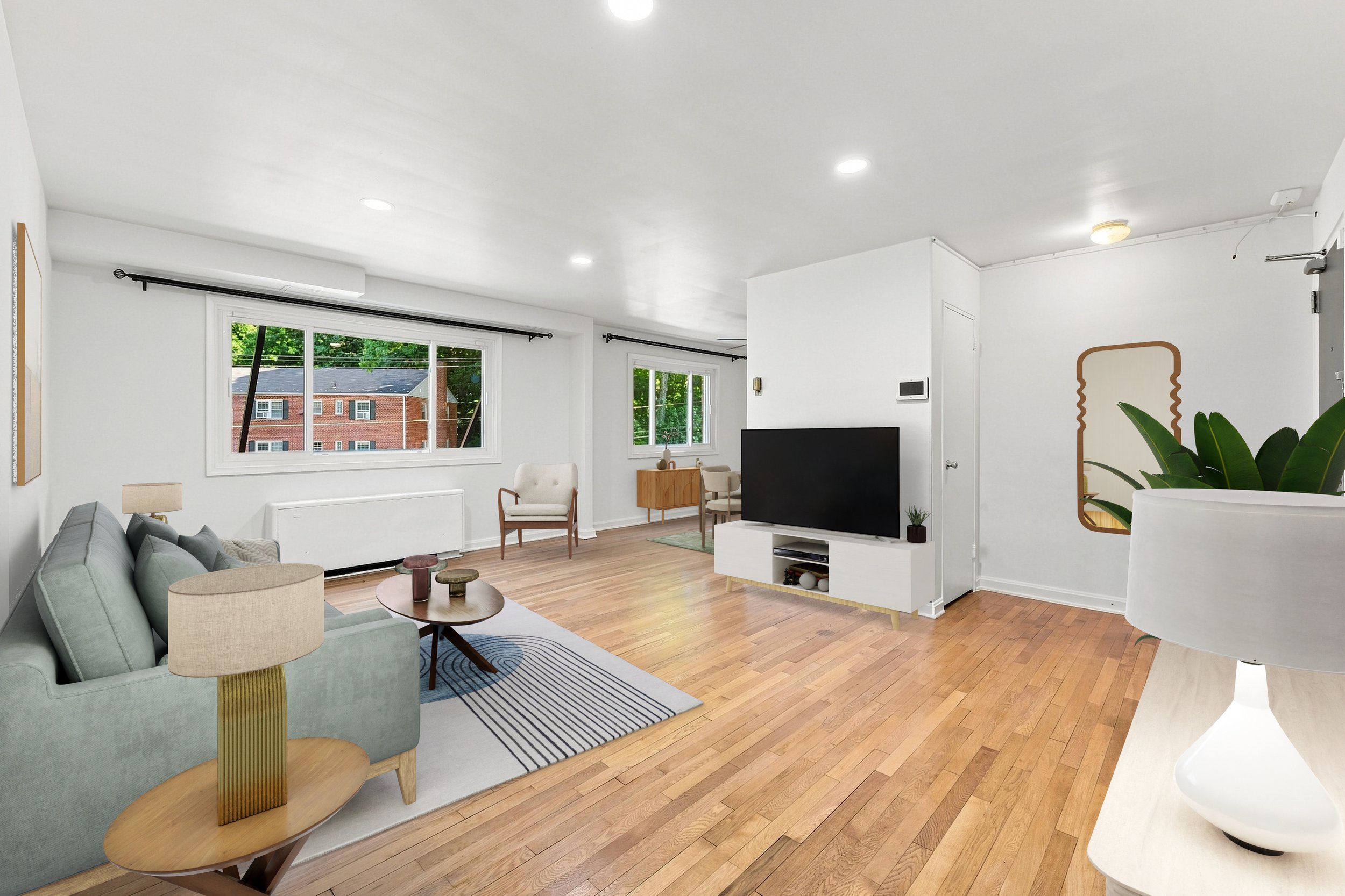 Bright open-plan living room in a DC-area apartment unit with hardwood floors and large windows