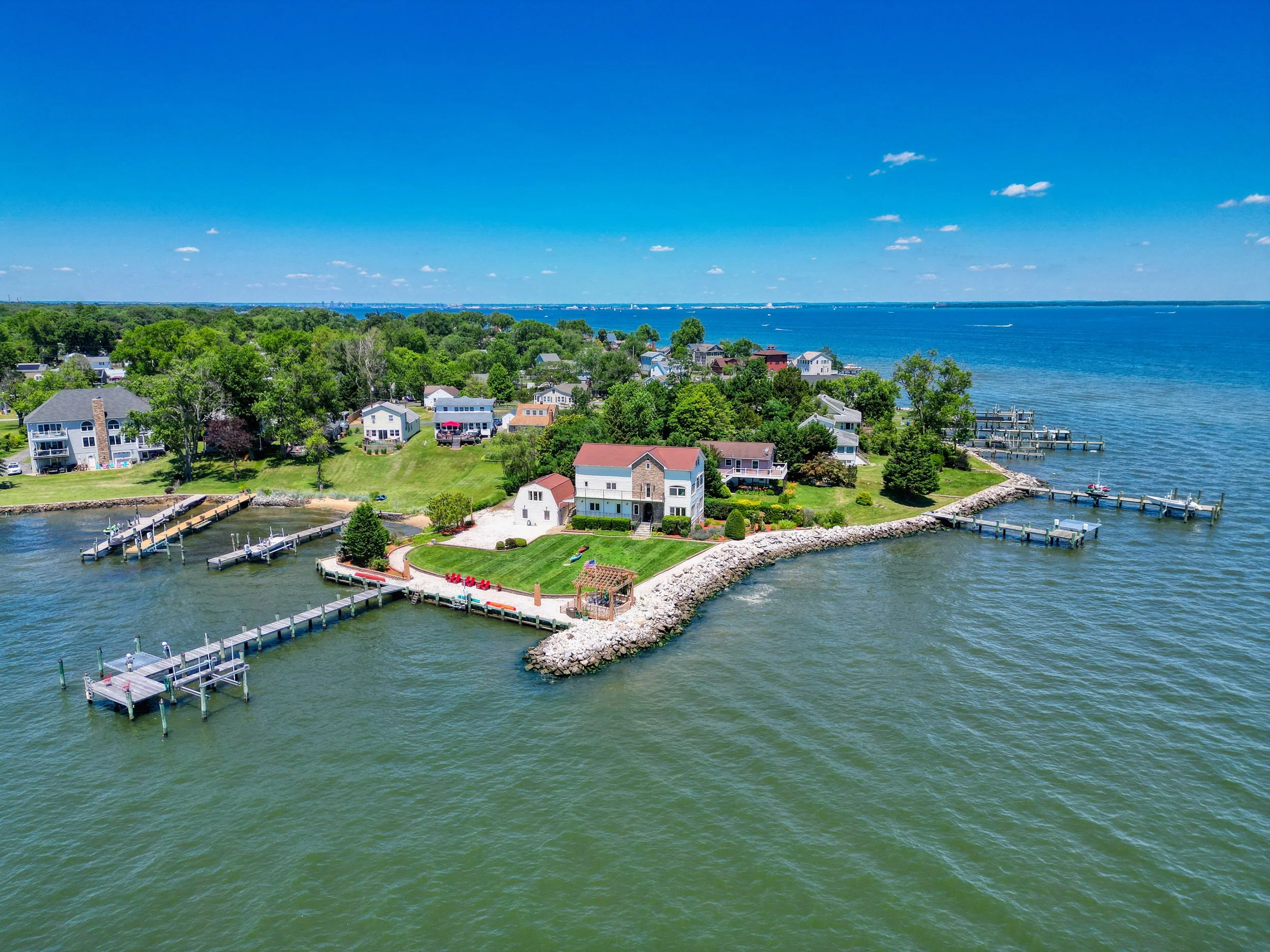 Aerial view of a waterfront home on a point lot with private docks extending into the bay.