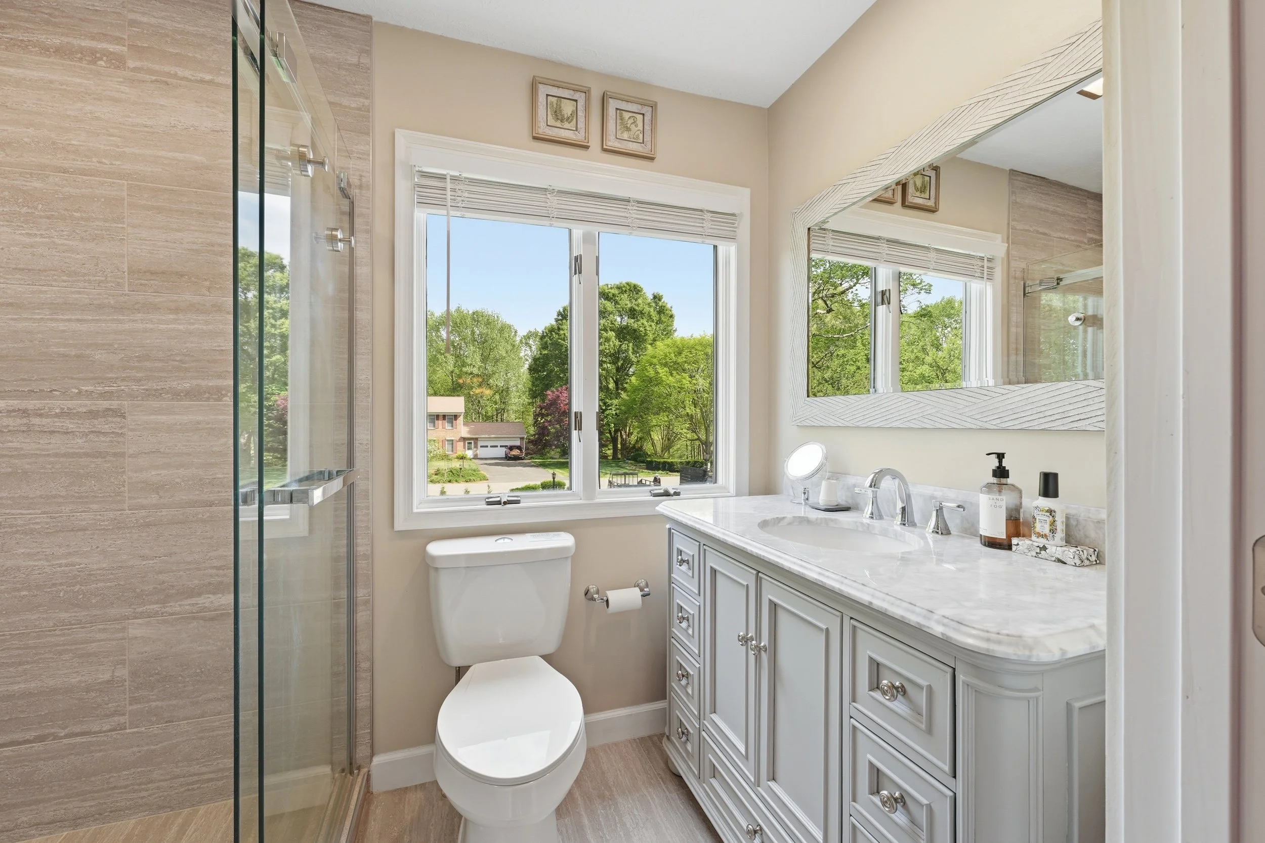 Bathroom with marble-top vanity and glass shower photographed for a home listing.
