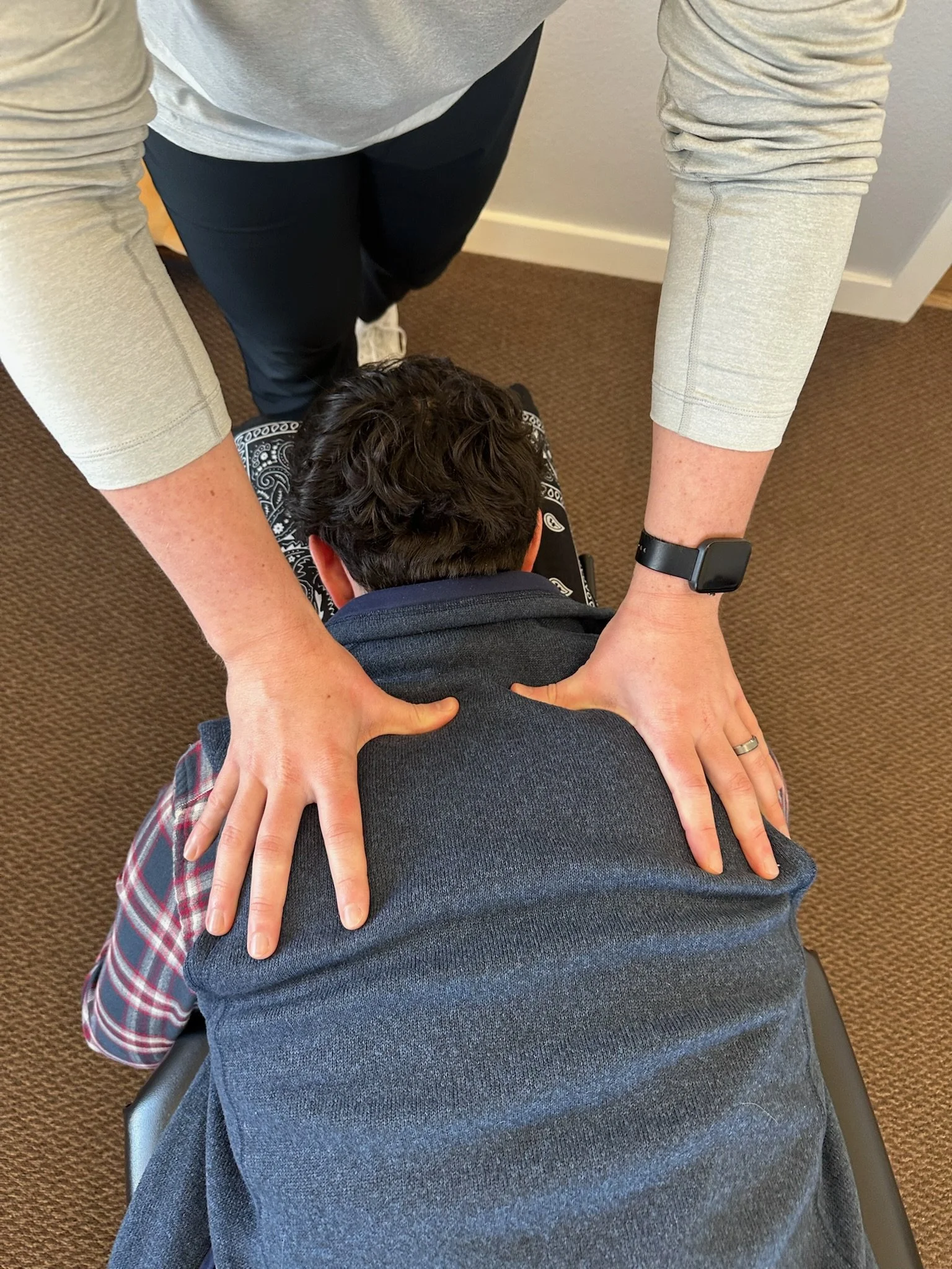 Chiropractor performs upper back adjustment on active adult patient in Colleyville clinic