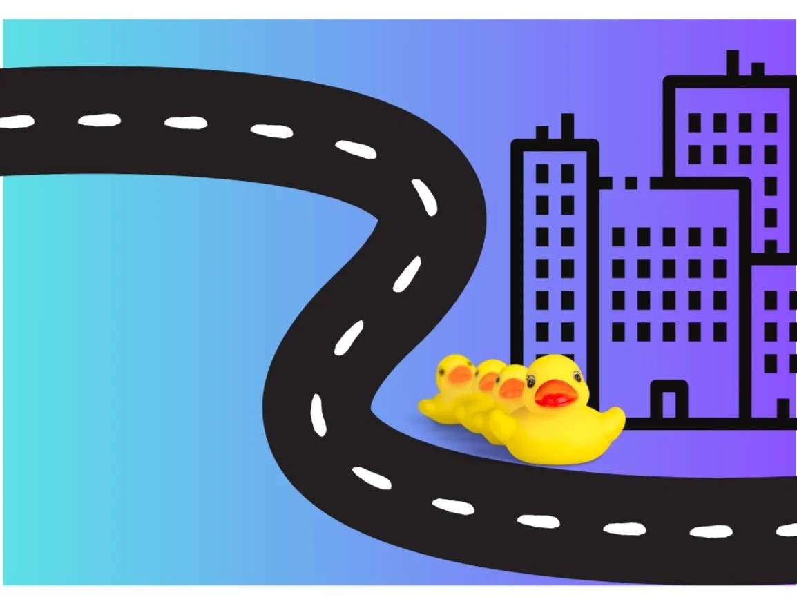 Rubber duckies in a row along a road in a city.