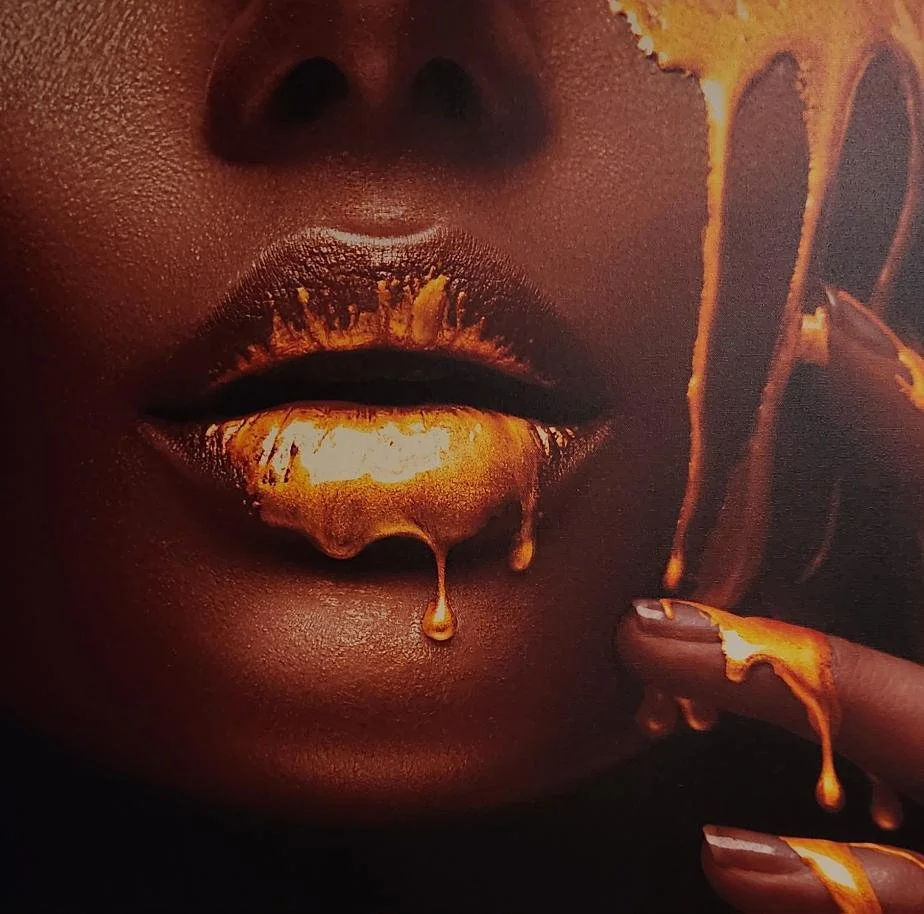 Close-up of a person's lips and lower face with melting gold-like makeup around the mouth, gold dripping from the lips and fingertips.