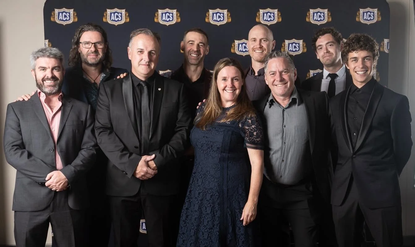 Group of ten people at a formal event, standing in front of a step and repeat banner with logos of ACS Awards, smiling for the camera.