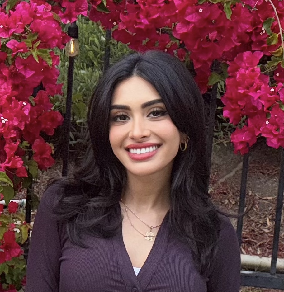 Dr. Tina Halabian, PsyD, licensed clinical psychologist, smiling outdoors in front of pink bougainvillea flowers