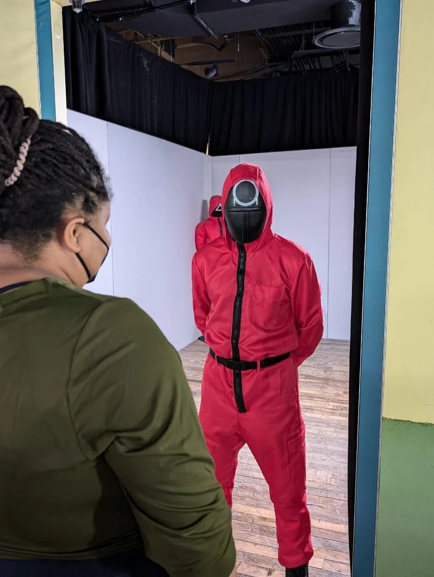 Photo of a guard at the NYC SquidGames PopUp facing the camera and Dr. Forté.