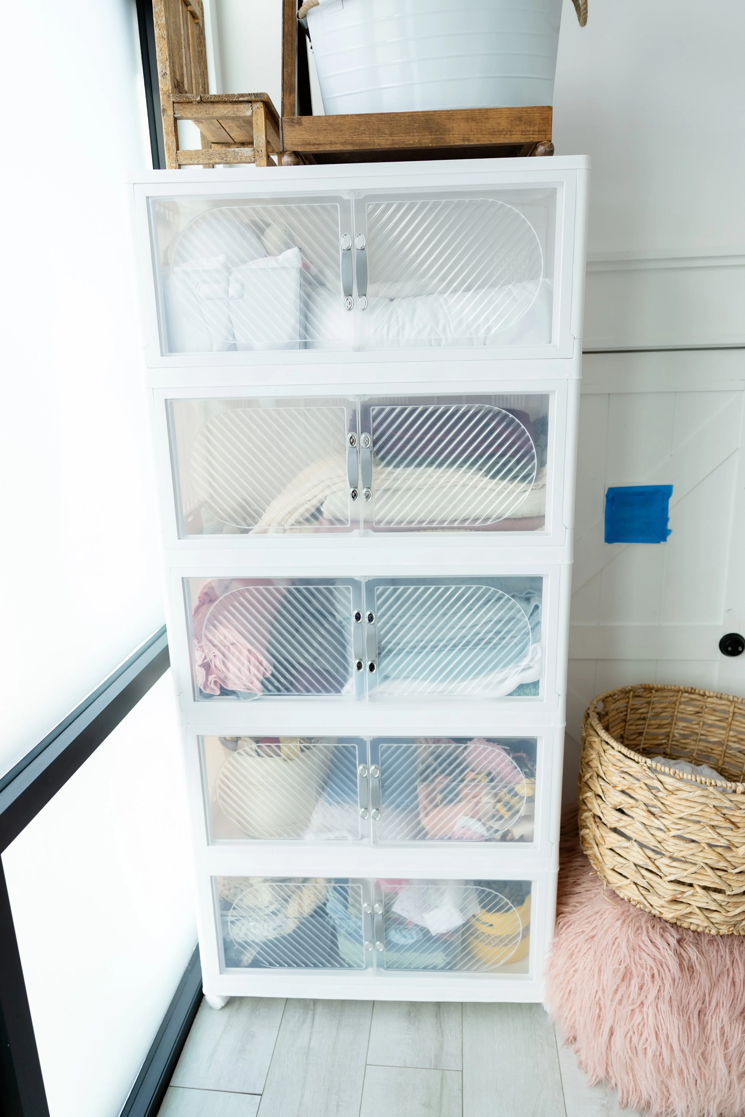 White storage drawers in Studio C at Blank Space American Fork filled with neatly organized newborn wraps, blankets, and posing fabrics in neutral and pastel tones.