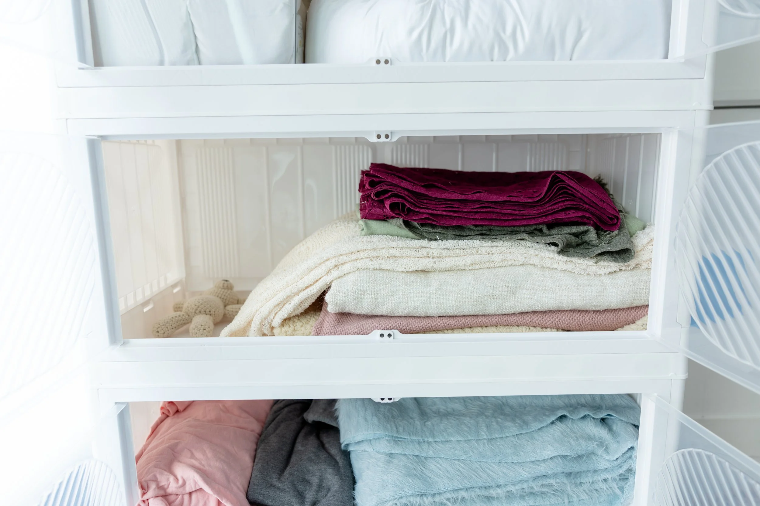 Folded newborn photography wraps and blankets organized in white studio drawers in Studio C at Blank Space in American Fork, Utah.