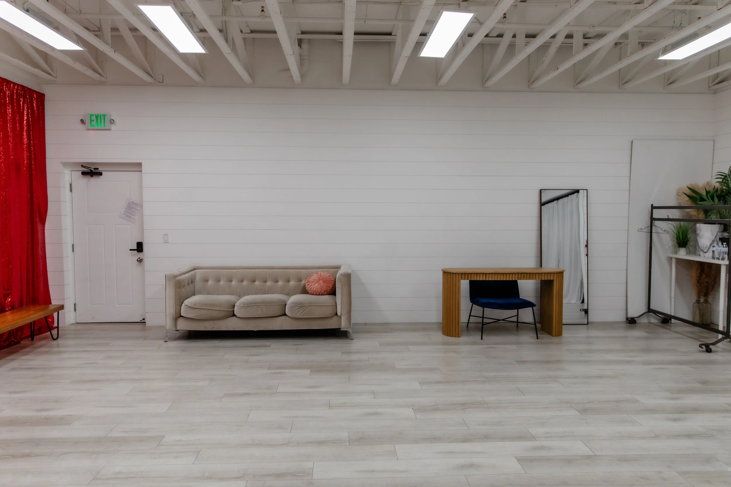 Studio B at Varsa Studios in American Fork, Utah featuring a white shiplap wall, neutral couch, styling desk, and open floor space, ideal for photographers and content creators shooting branding sessions, lifestyle portraits, and editorial content.
