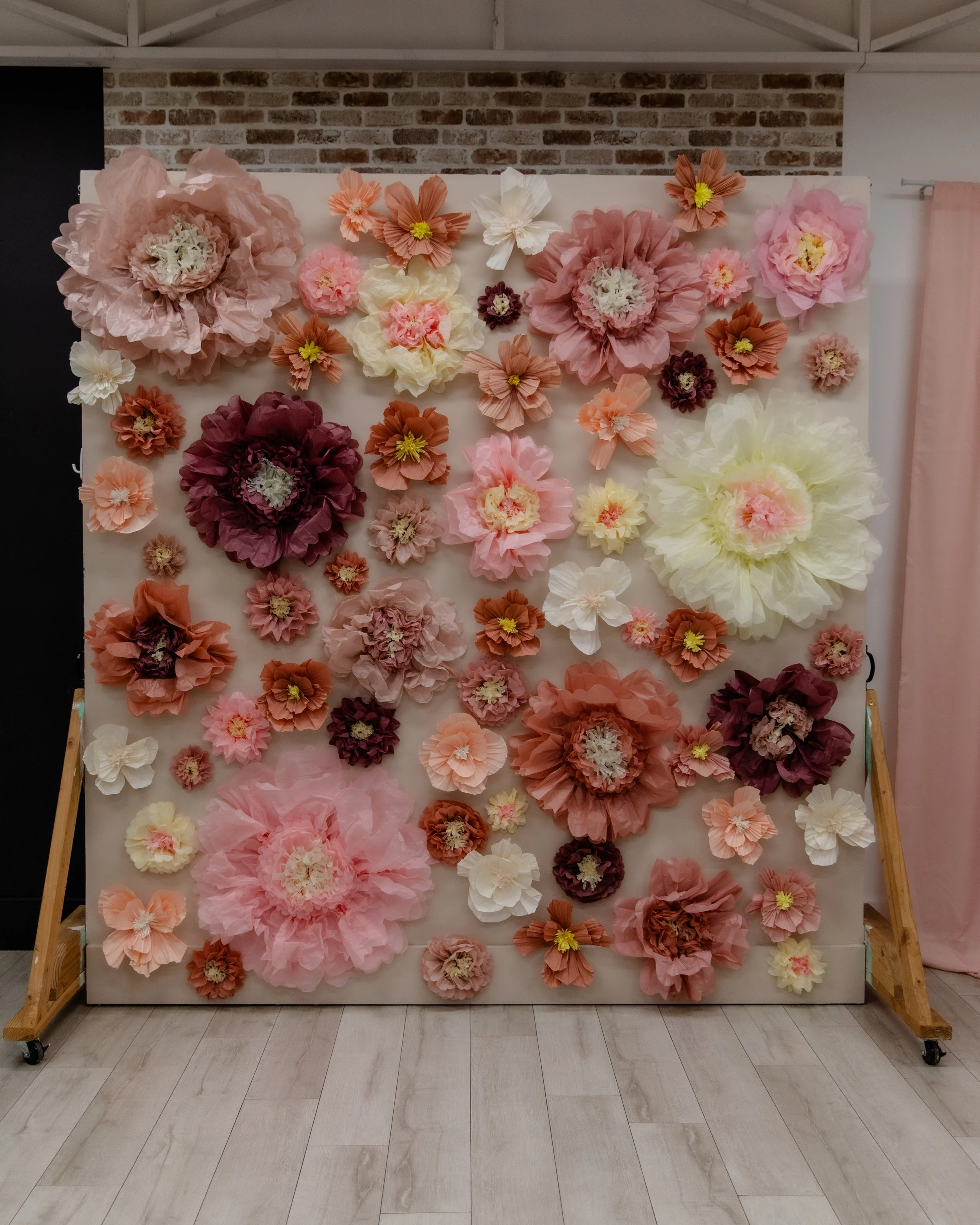 This oversized floral feature wall inside Studio A at Varsa Studios in Blank Space American Fork is designed for statement sessions. The dimensional paper flowers in blush, peach, ivory, and deep rose tones create a romantic, elevated backdrop perfec