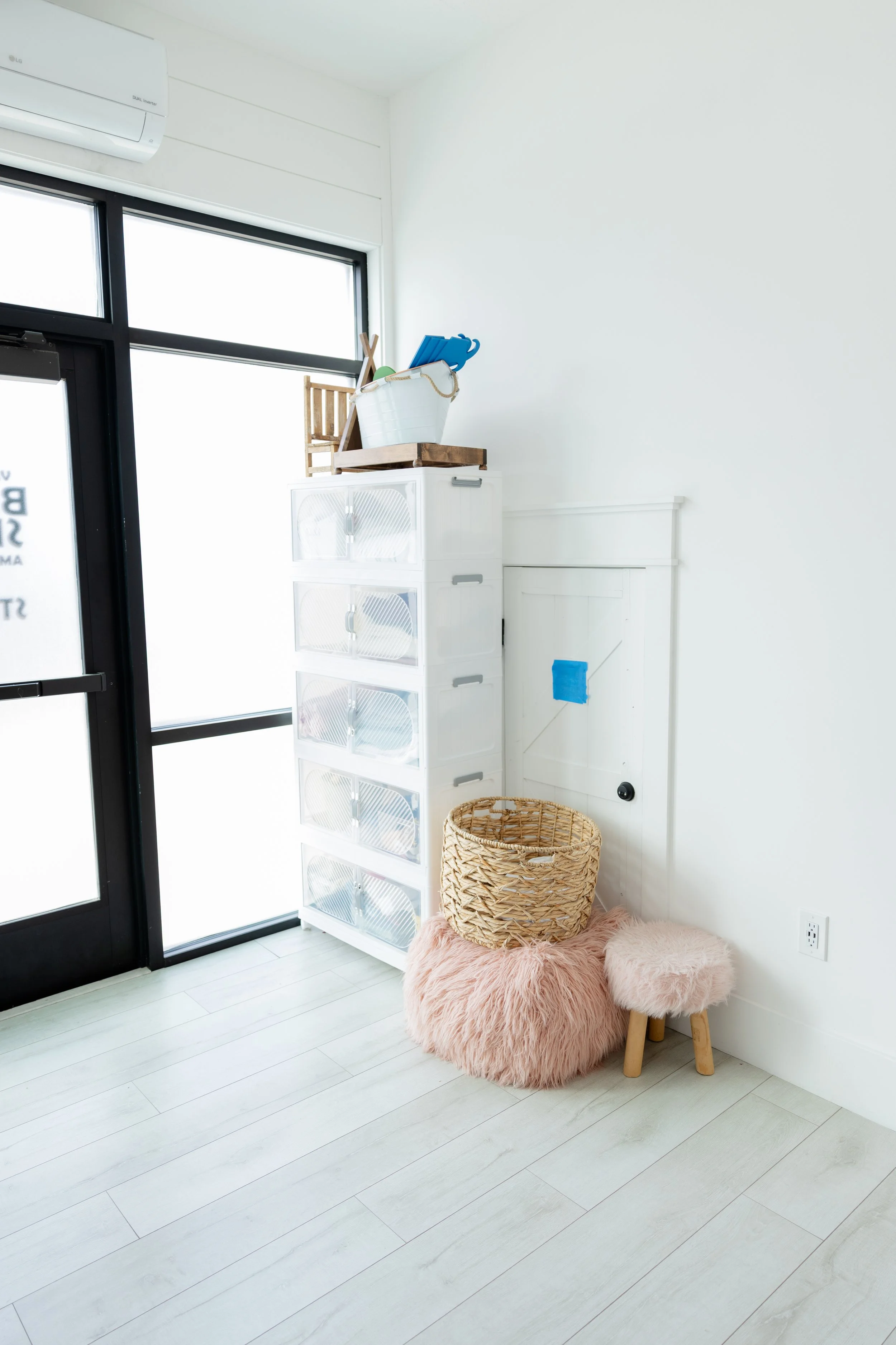 Organized newborn photography prop storage in Studio C at Blank Space American Fork, featuring white drawers, baskets, stools, and natural light for seamless newborn sessions.