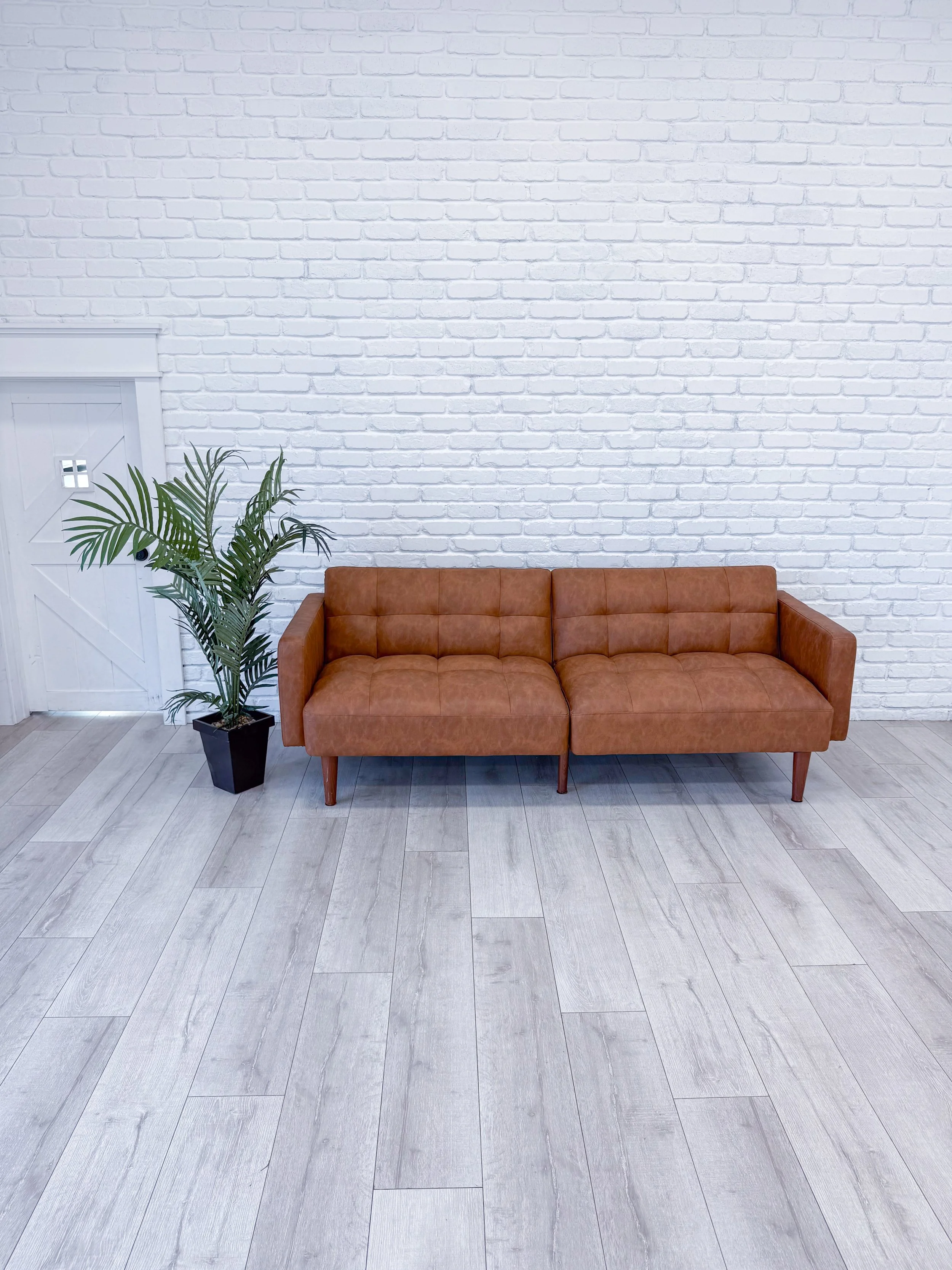 Bright white painted brick wall paired with a modern brown leather sofa creates a timeless photography backdrop. Ideal for family photos, branding photography, professional headshots, couples sessions, content creation, business marketing photos, and