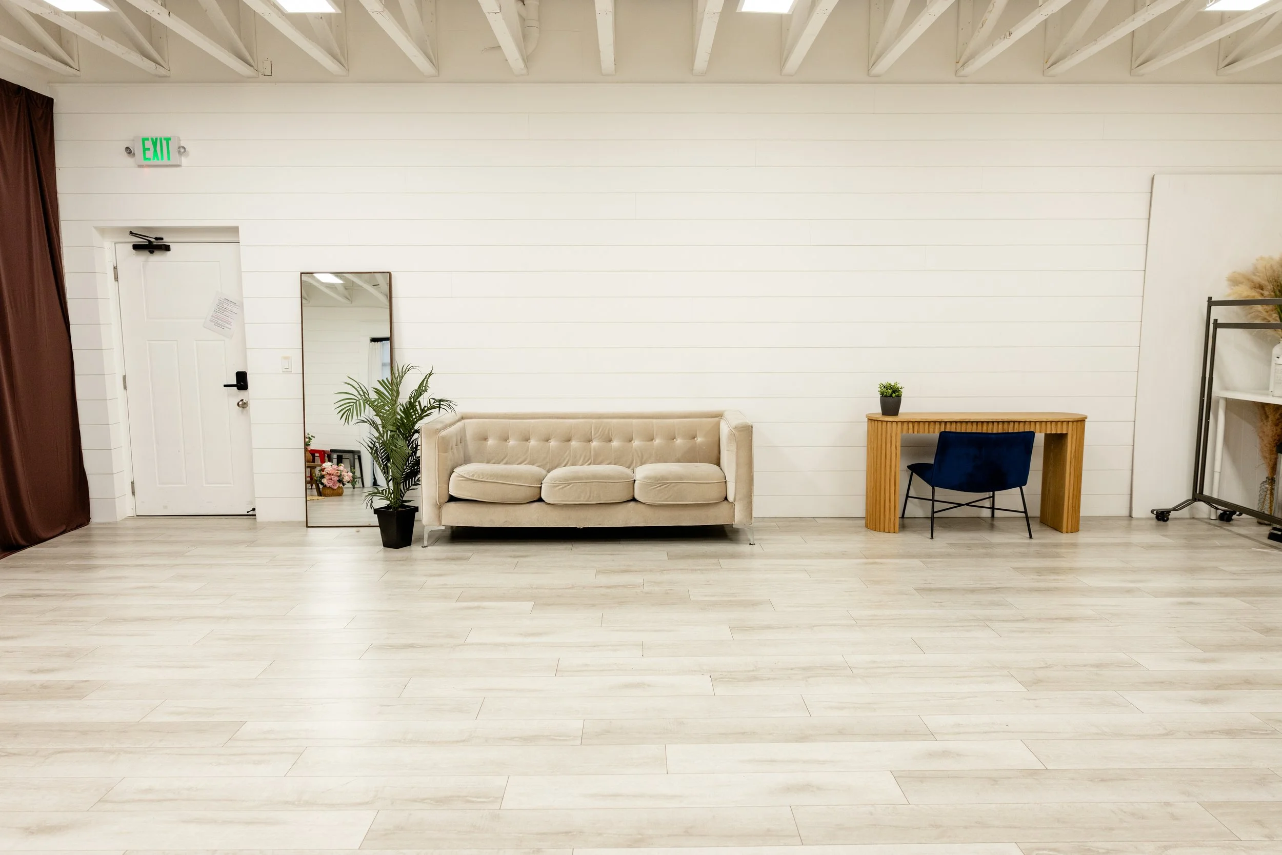 Modern neutral lounge and workspace setup inside Studio A at Varsa Studios American Fork Utah, branding session studio rental with beige sofa, wood desk, natural light and open floor plan for headshots, business content creation and photography studi
