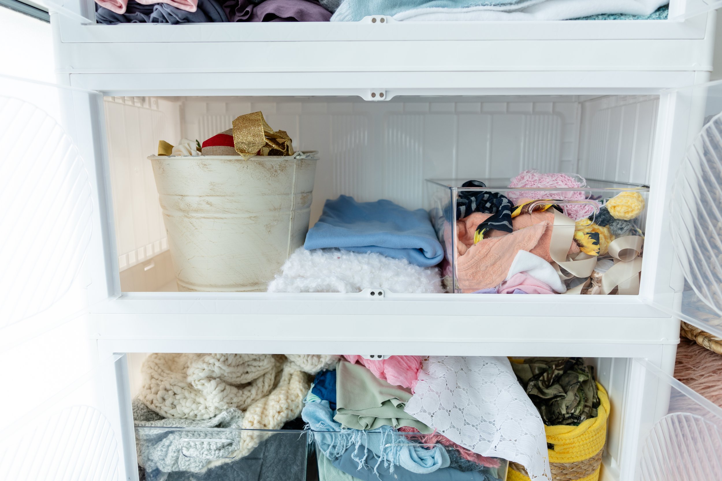 Open Studio C prop storage drawers at Blank Space American Fork displaying newborn photography accessories, textured fabrics, wraps, and small styling details.