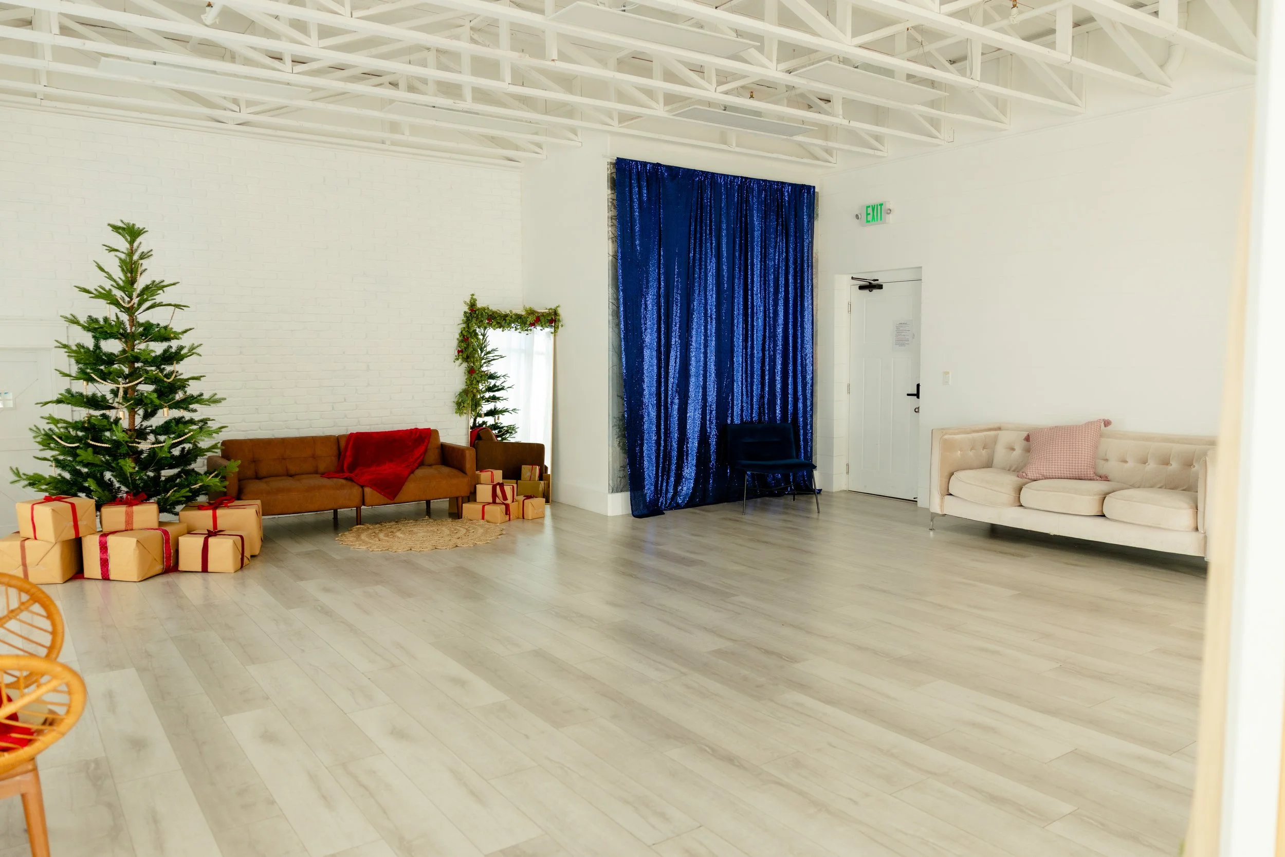 A bright open studio with benches and a fabric draped bed, sheer curtains, and ample room for photoshoots.