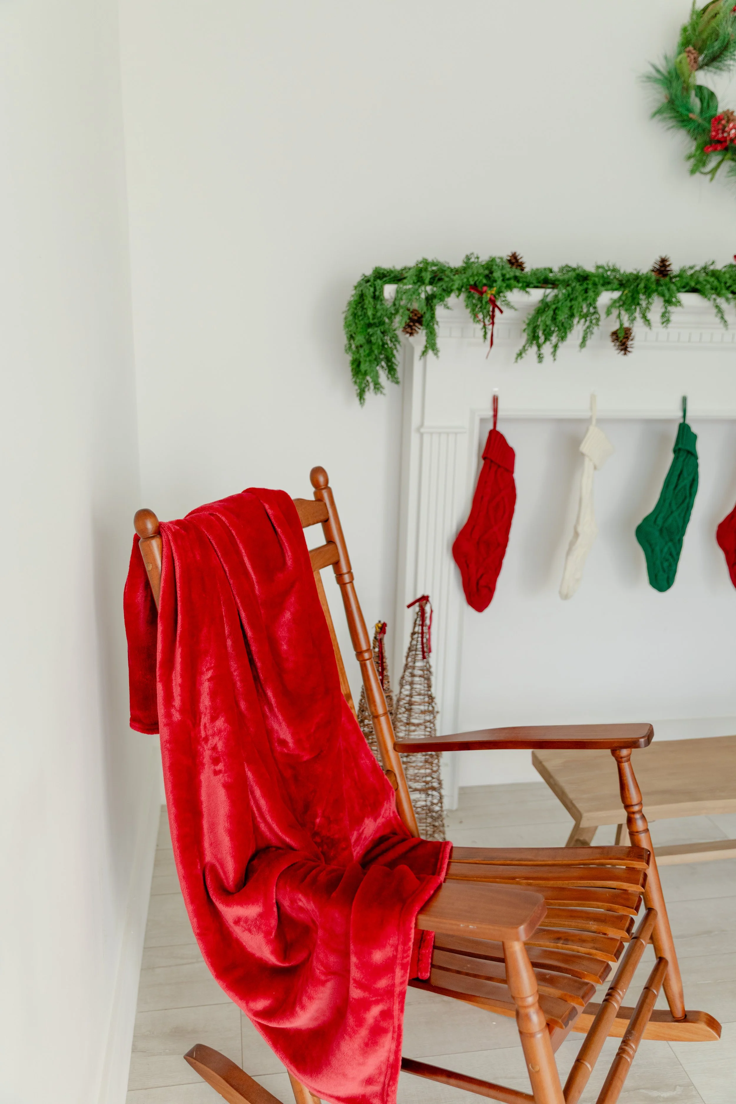 A cozy Christmas detail inside Studio C at Varsa Studios, American Fork, Utah — perfect for photographers and creators seeking warm, nostalgic holiday imagery. This setup features a classic wooden rocking chair draped in a red velvet throw beside a f