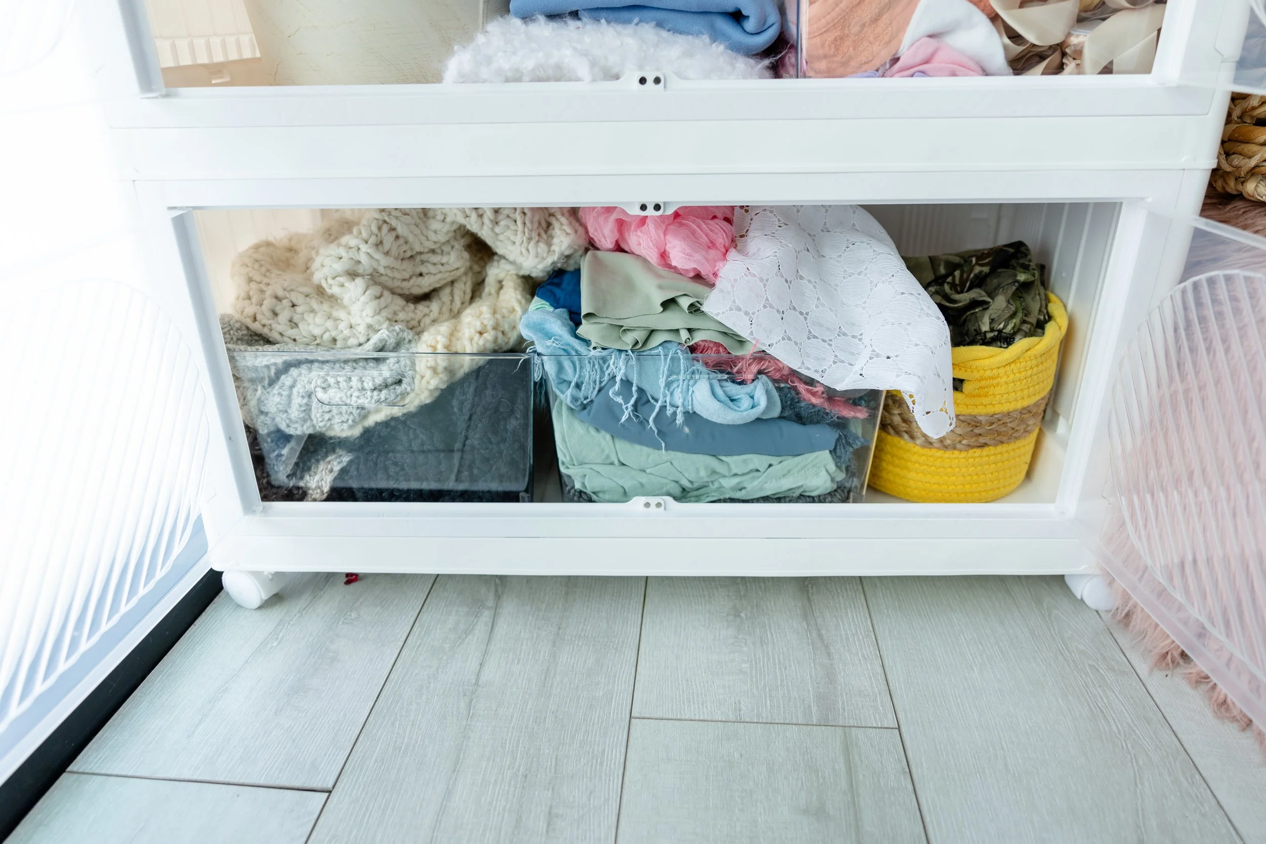 Lower storage drawers in Studio C at Blank Space American Fork filled with layered newborn photography fabrics, knits, lace, and neutral posing textiles.