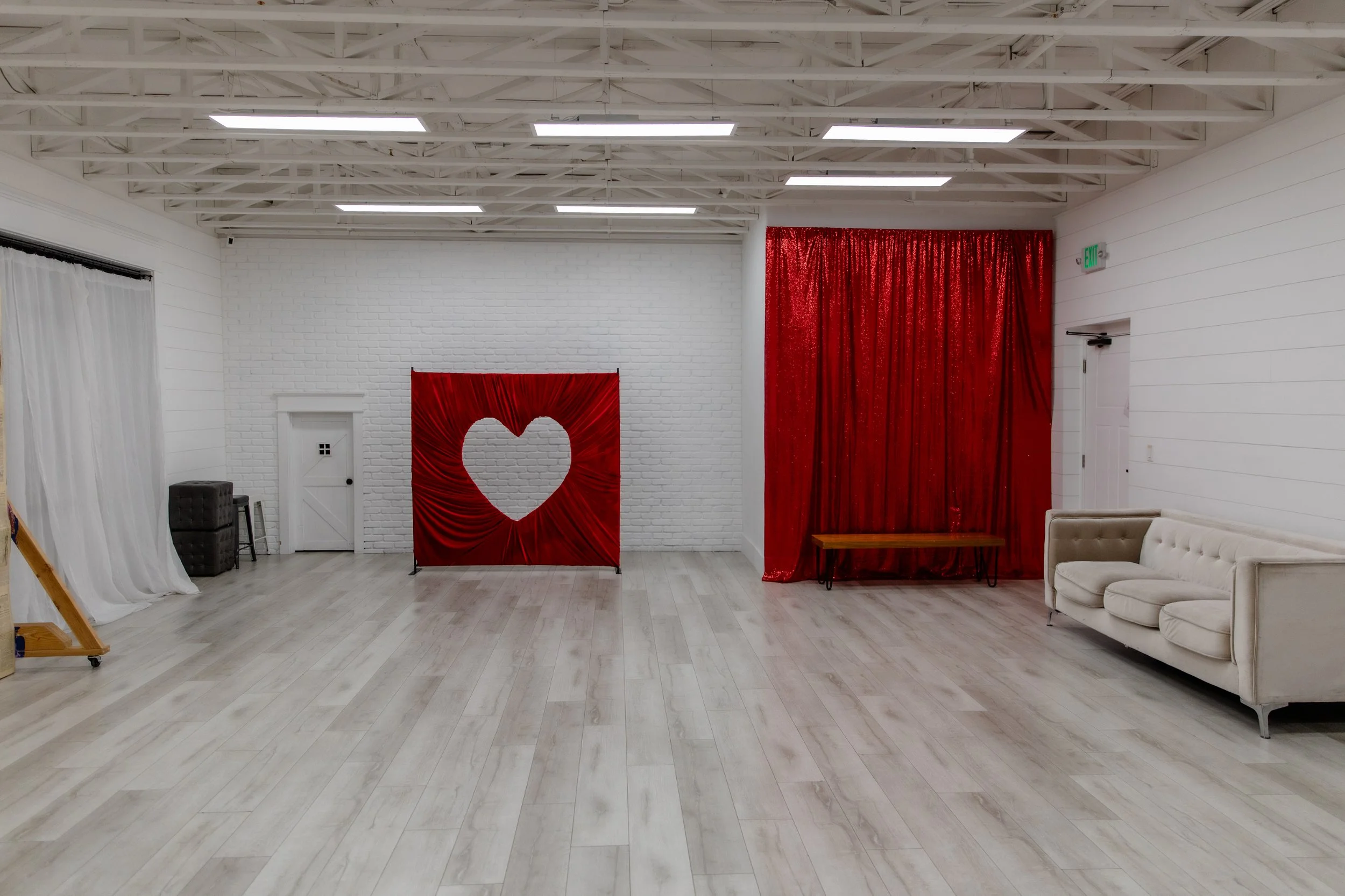 Full overview of Studio B at Varsa Studios in American Fork showcasing red sequin curtains, heart cutout backdrop, neutral couch, and open floor space for photographers, videographers, and content creators.