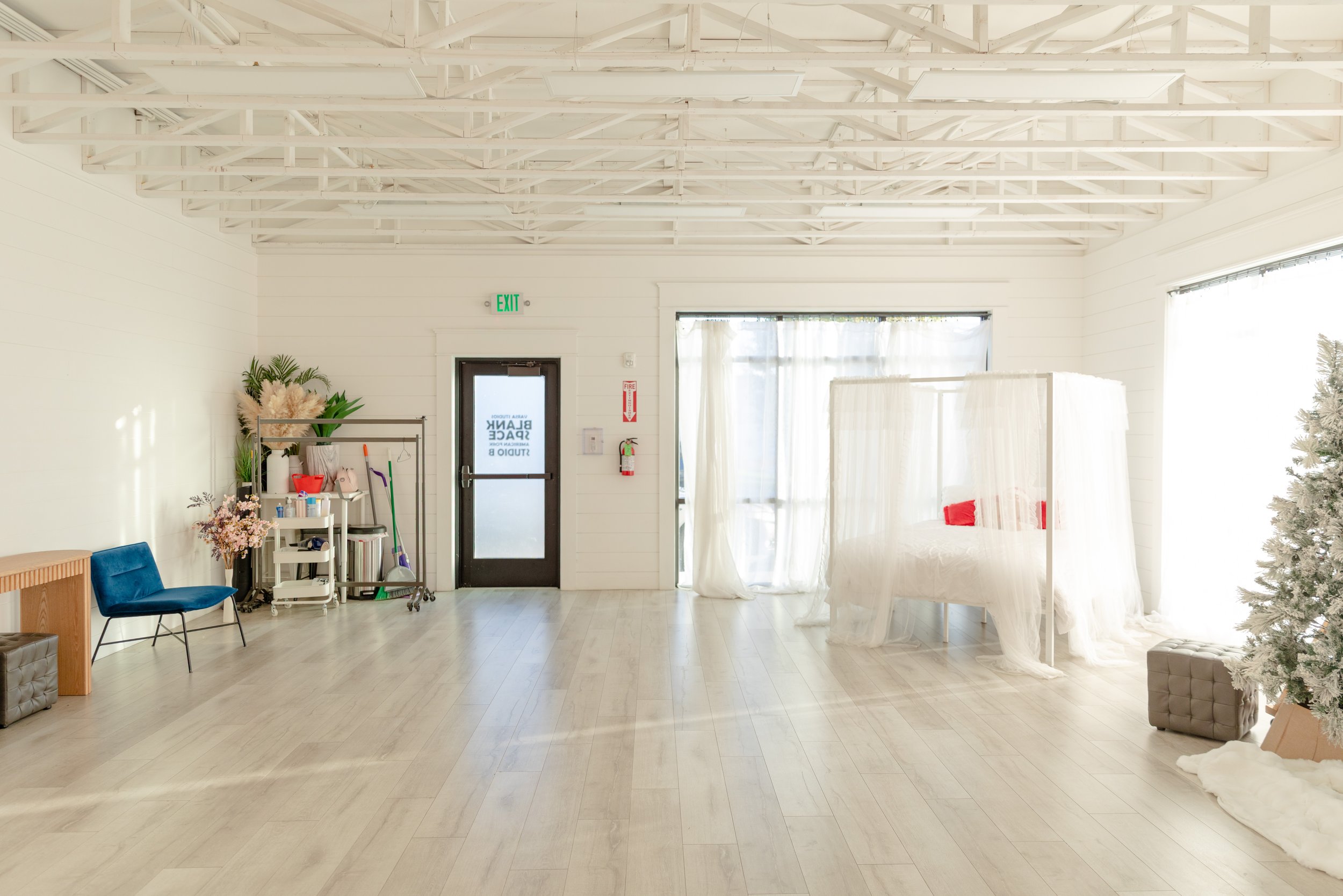 Studio B at Varsa Studios in American Fork, Utah, offers a bright, open space filled with soft natural light—ideal for photographers, videographers, and content creators. This setup features a white canopy bed with sheer drapes, a flocked Christmas t