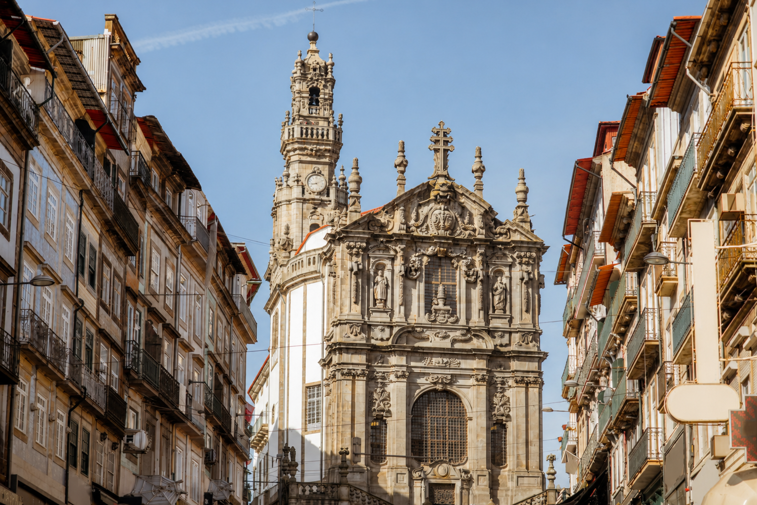 Clérigos Church and Tower in Porto, Portugal, rising above a historic city street with ornate Baroque architecture and traditional Portuguese buildings.