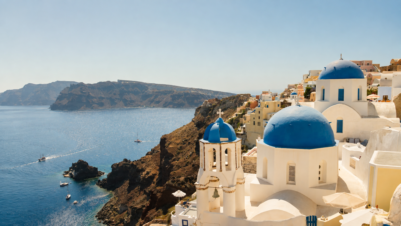 Blue-domed churches overlooking the Aegean Sea and Santorini caldera in Greece