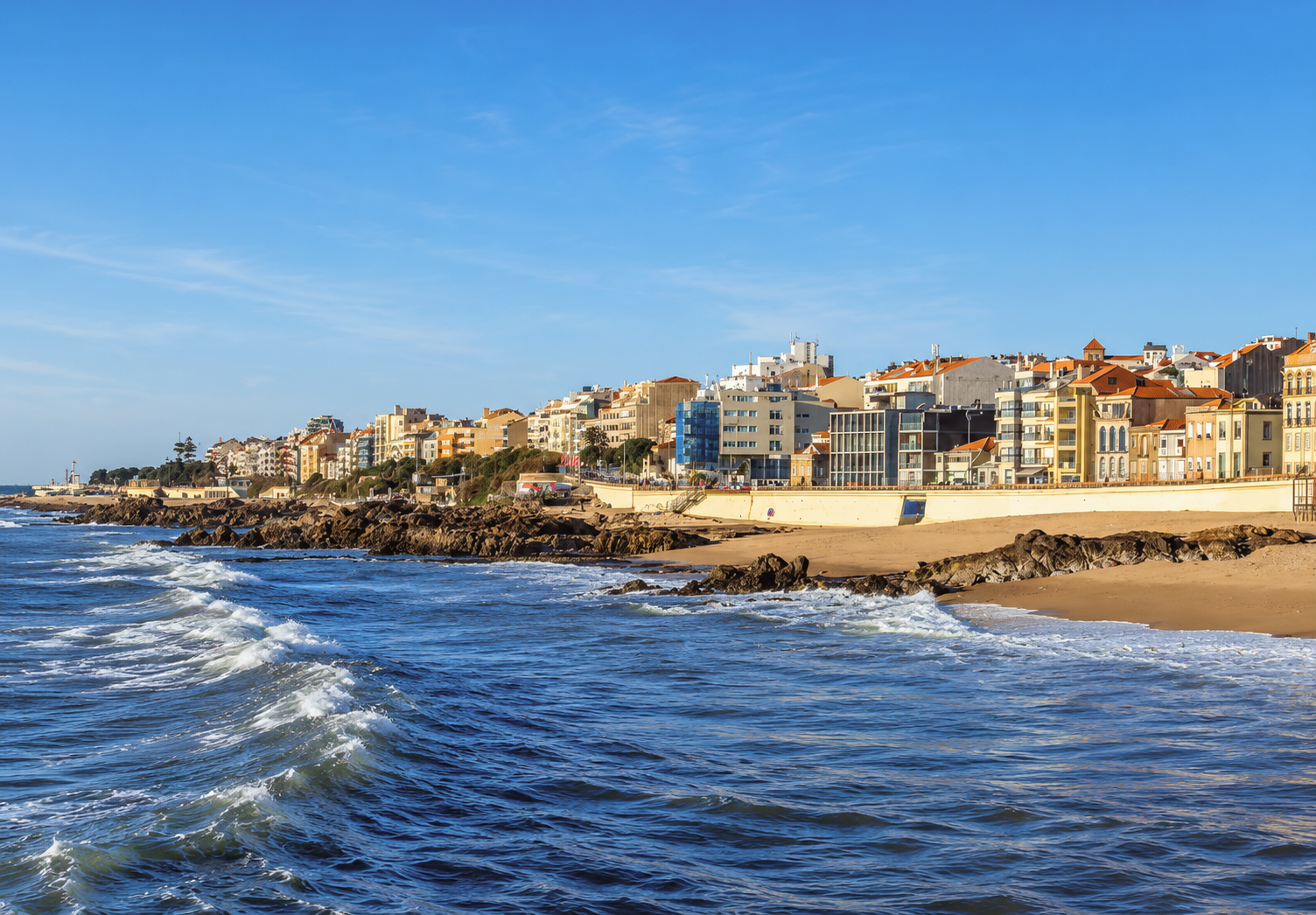 Foz do Douro coastline in Porto, Portugal, with Atlantic Ocean waves, sandy beaches, and colorful waterfront buildings along the seaside promenade.