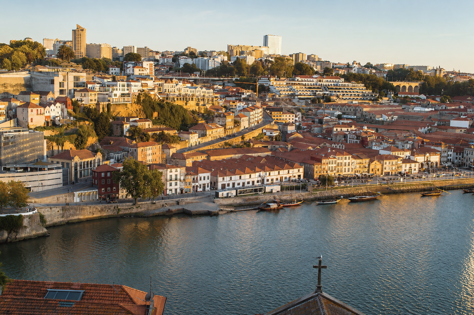 Golden-hour view of Porto, Portugal, with historic hillside buildings, terracotta rooftops, and the Douro River waterfront.