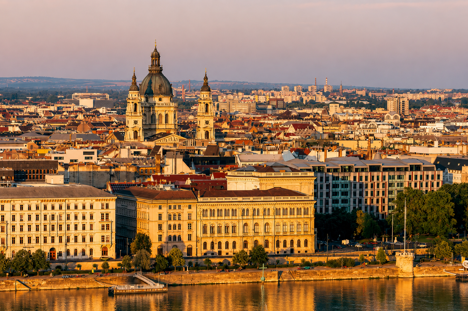 Budapest, Hungary cityscape featuring St. Stephen’s Basilica, historic architecture, and the Danube riverfront illuminated by warm golden-hour light.