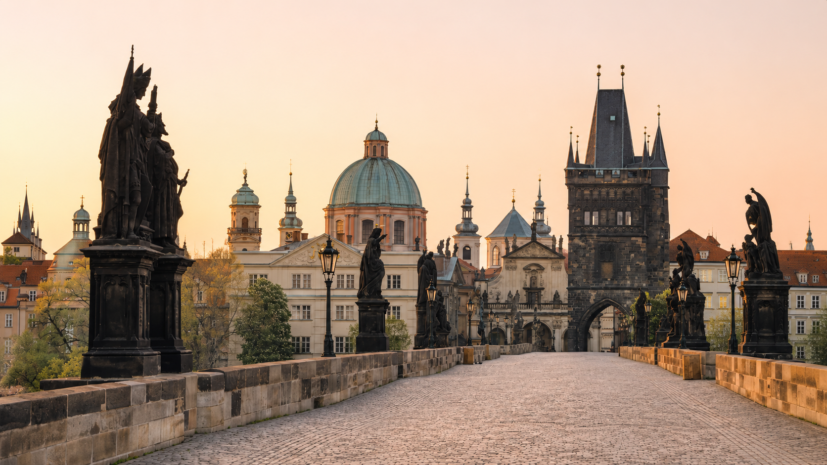 Charles Bridge in Prague, Czech Republic, at sunrise with historic statues, the Old Town Bridge Tower, and baroque architecture of Prague’s Old Town.
