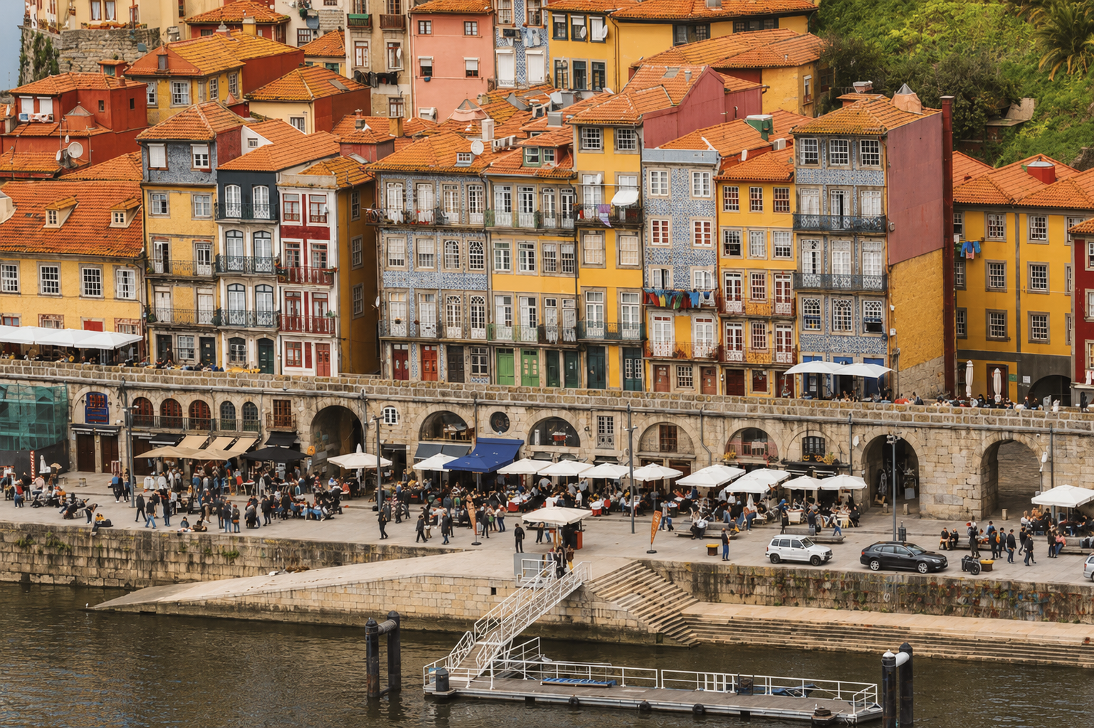 Colorful historic buildings and waterfront cafés along the Ribeira district in Porto, Portugal, overlooking the Douro River.
