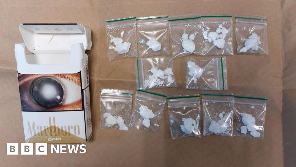 A pack of Marlboro Gold cigarette box and multiple small plastic bags filled with a white powdery substance