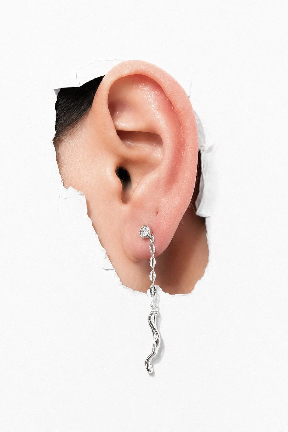 silver-wavy-huggie-hoop-earring-ear-through-torn-paper.png