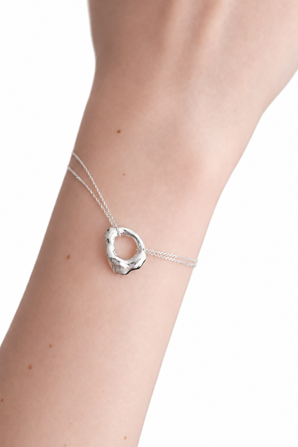 silver-organic-circle-pendant-bracelet-on-wrist.png