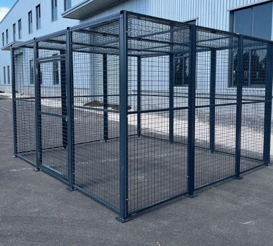 Empty black metal outdoor cage with wire mesh walls and door, placed on asphalt outside a modern building.