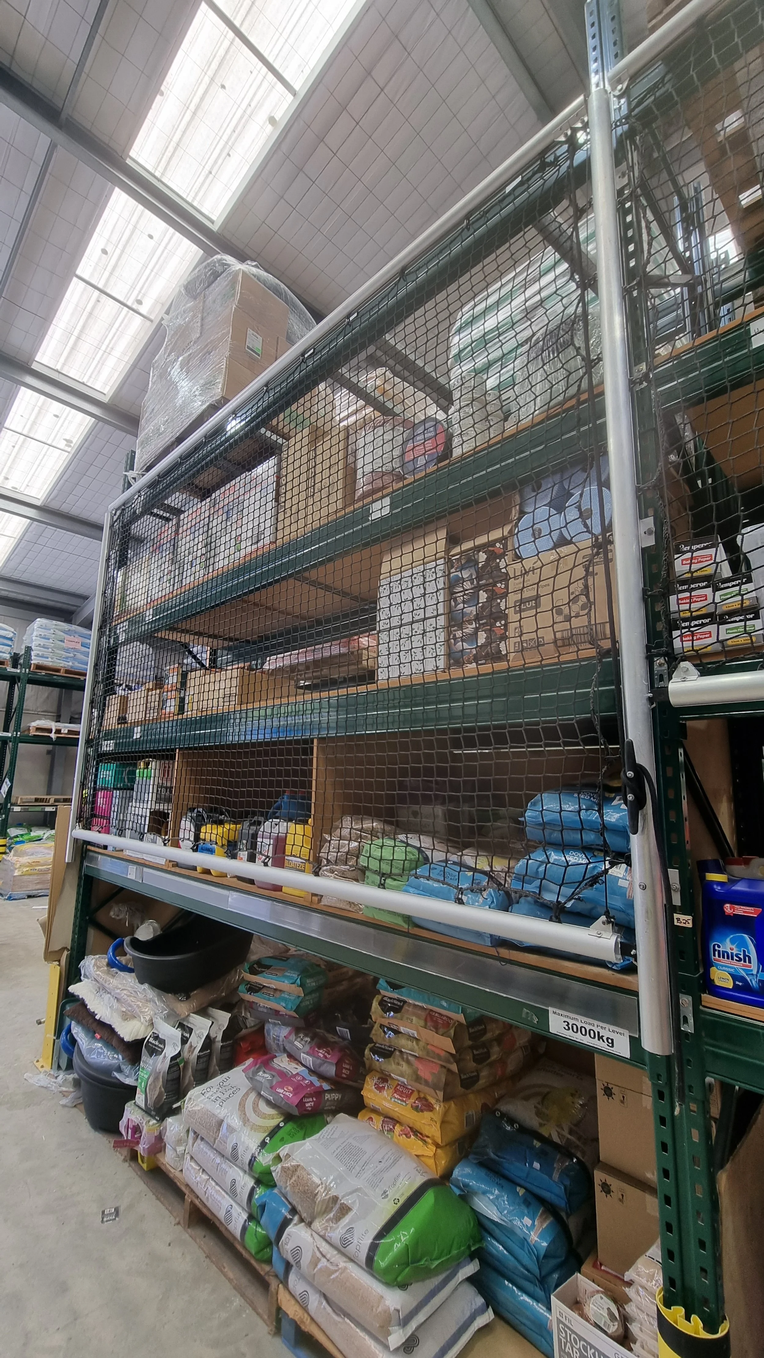 Shelving unit in a warehouse stocked with pet supplies such as bags of dog food, cleaning supplies, and other miscellaneous items.