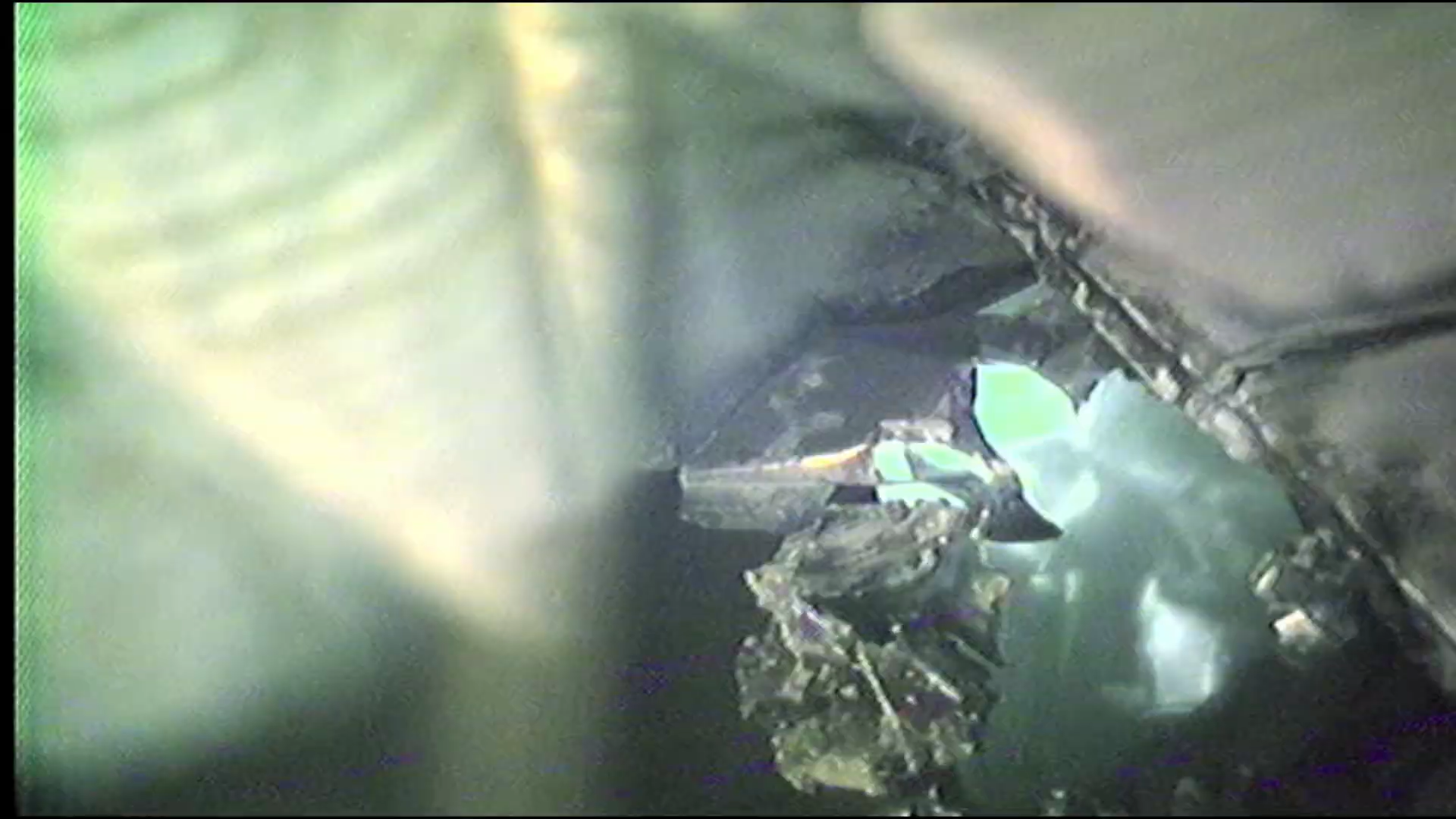 Close-up view of shattered glass, with reflective surfaces and light reflections.