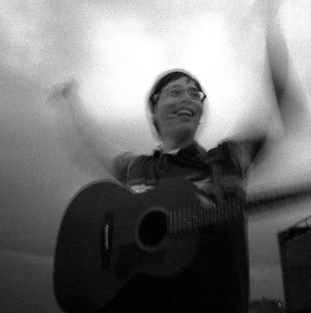 Person smiling and playing guitar indoors