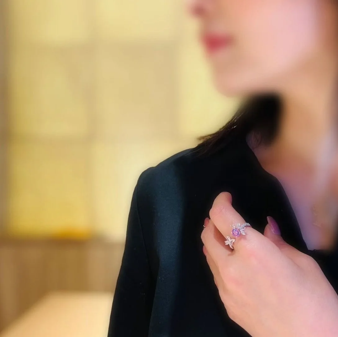 女性が黒い服を着ていて、指には紫色の宝石がついたリングをはめている。