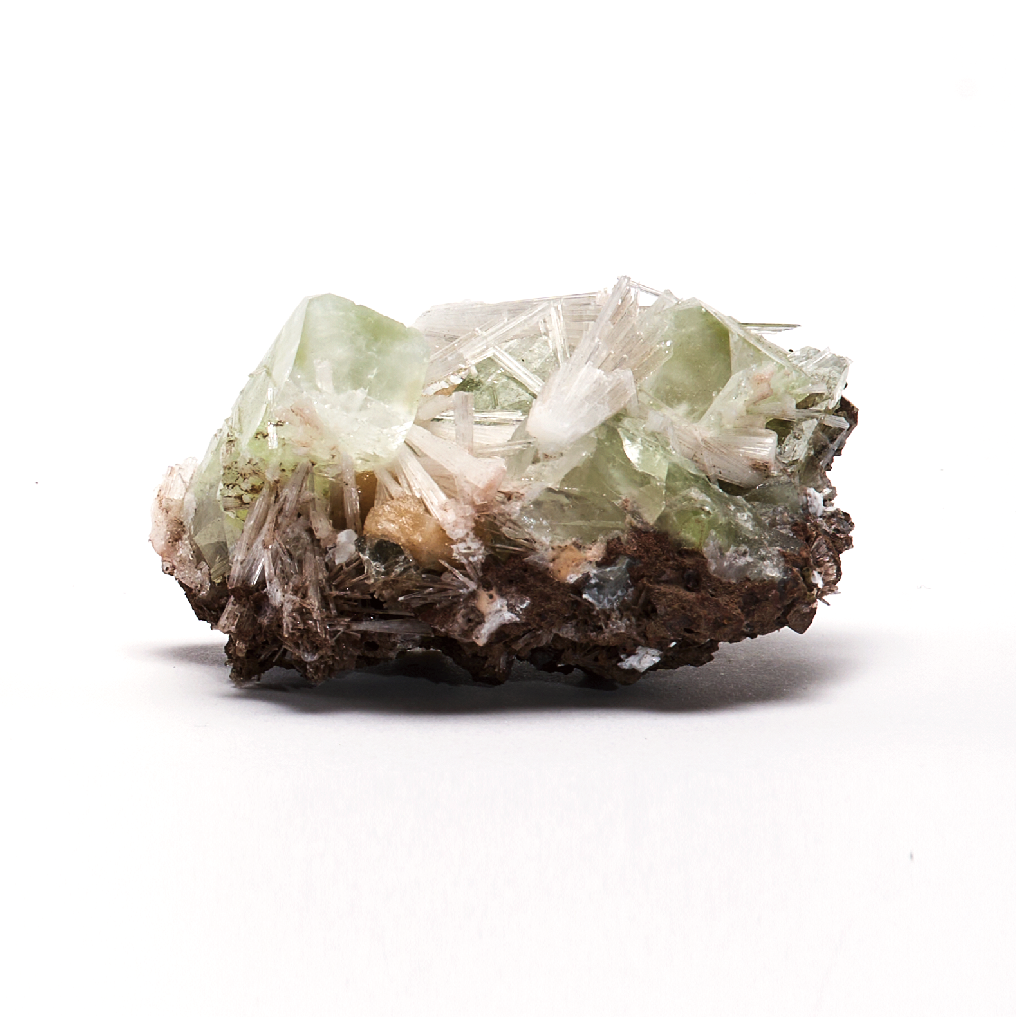 緑色の鉱石の塊が白い背景に置かれている、グリーンアポフィライト、スコレサイト、スティルバイト