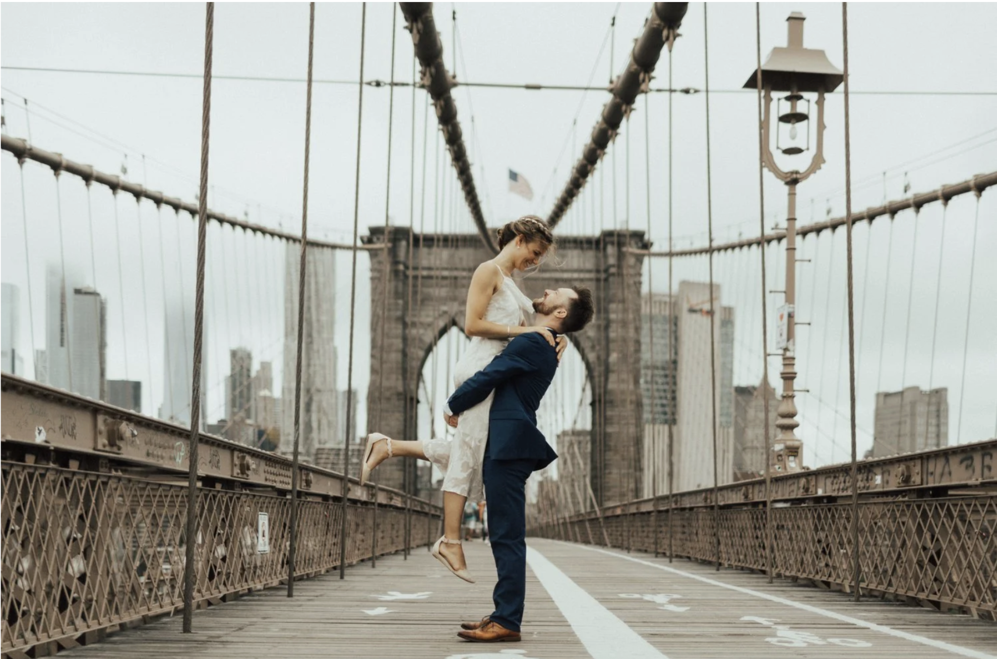 groom picking up bride in Notebook style on the Brooklyn bridge.