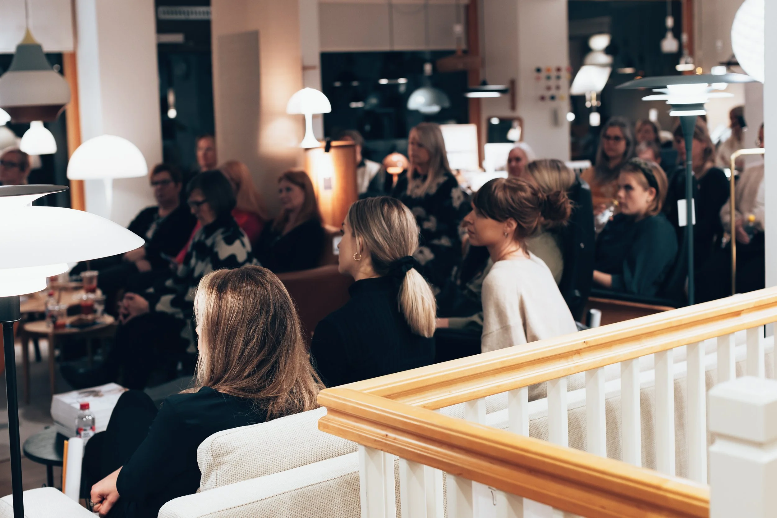People attending a presentation or conference in a cozy, well-lit room with modern decor.