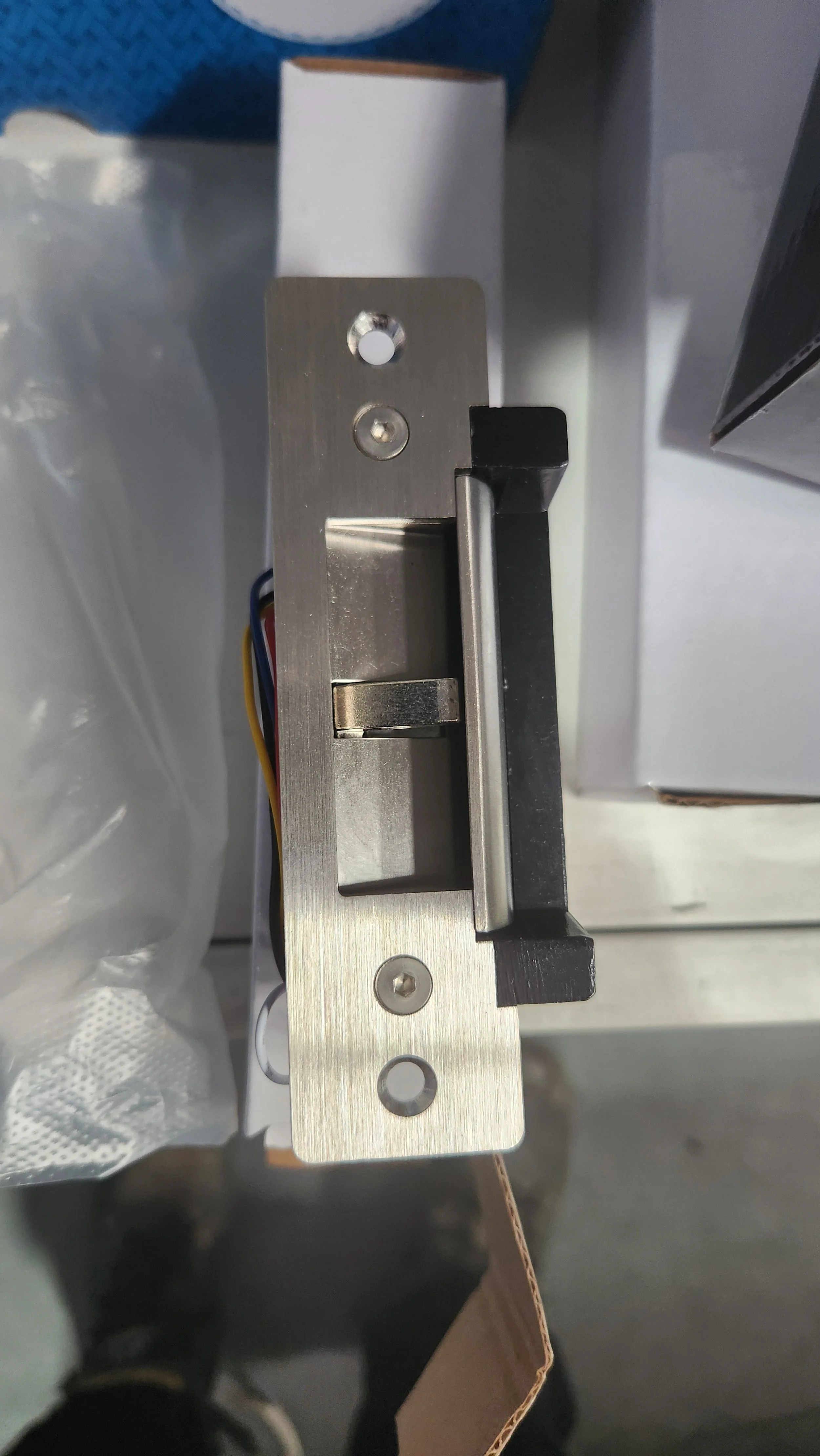 A metallic electronic lock mechanism with a latch and wiring, viewed from above.