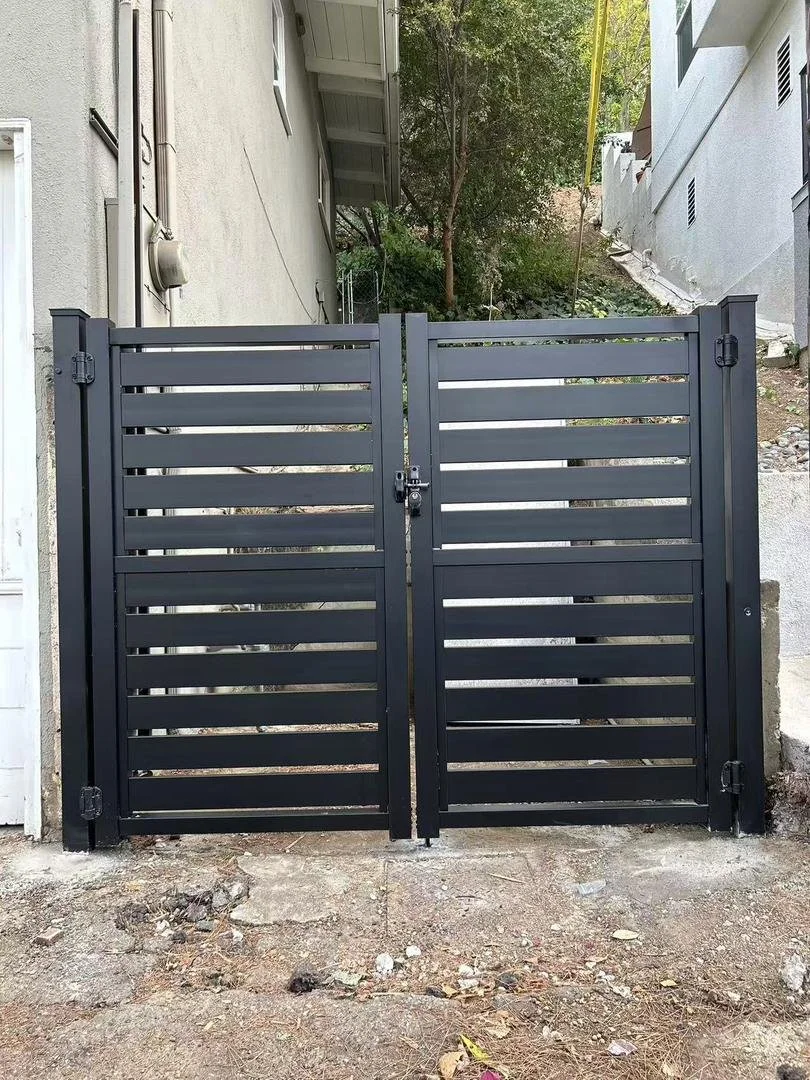 Black metal gate with horizontal slats installed at the entrance of a property, with a lock in the middle.