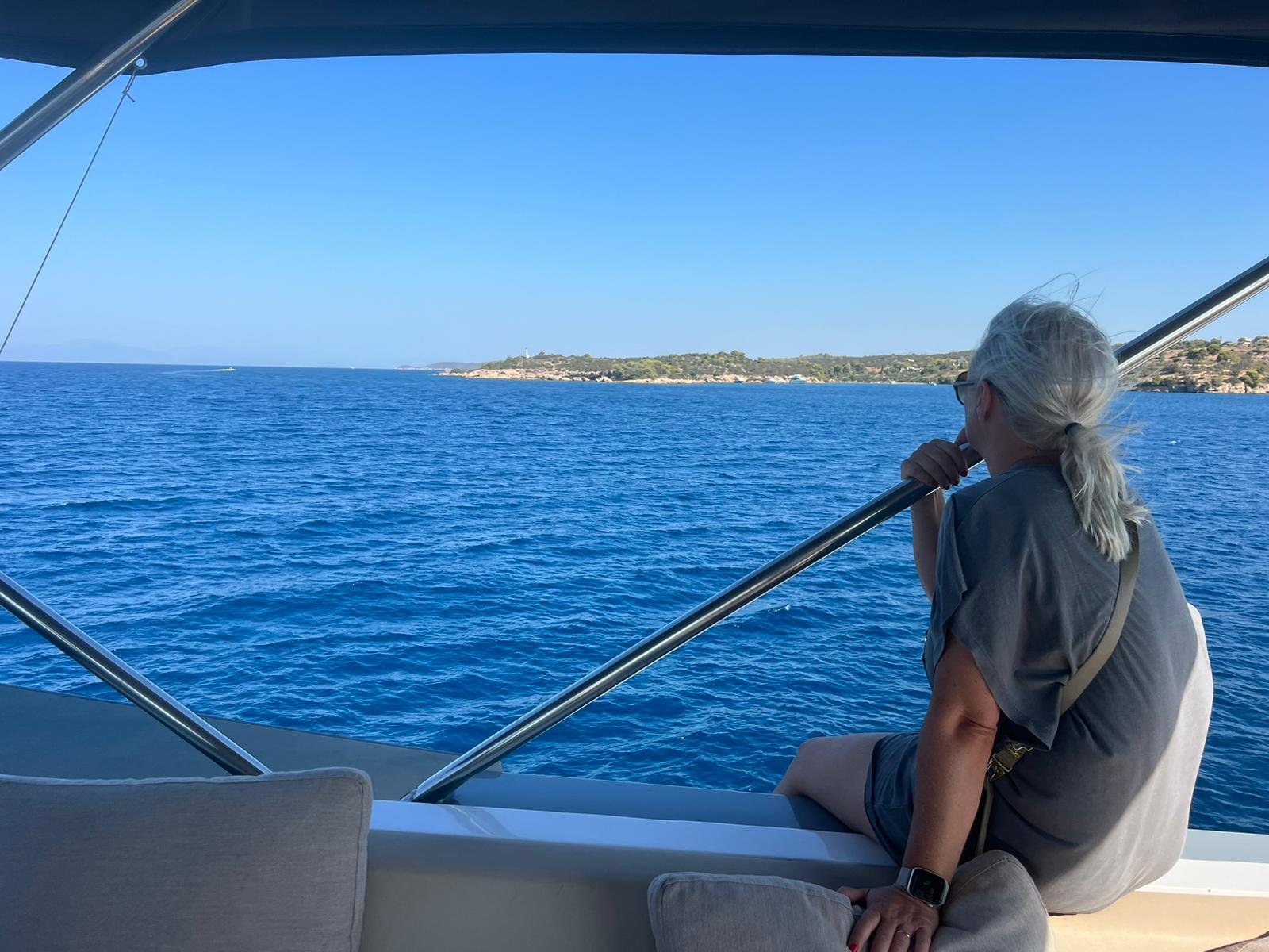 Frau auf einem Boot mit Aussicht auf das Meer und eine Küste