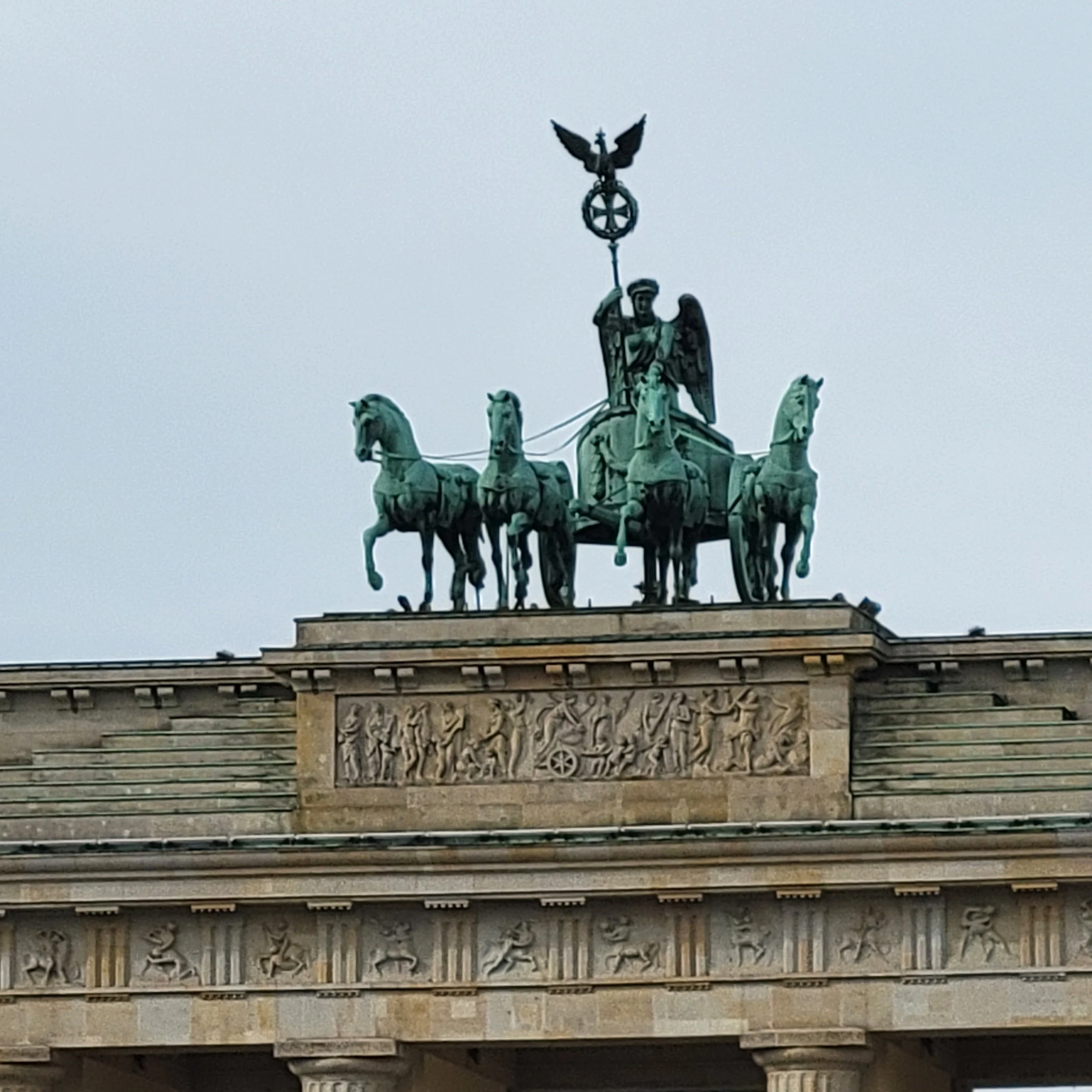 The Brandenburg Gate in Berlin, Germany, featuring the quadriga sculpture of a chariot drawn by four horses and driven by Victoria, the Roman goddess of victory.