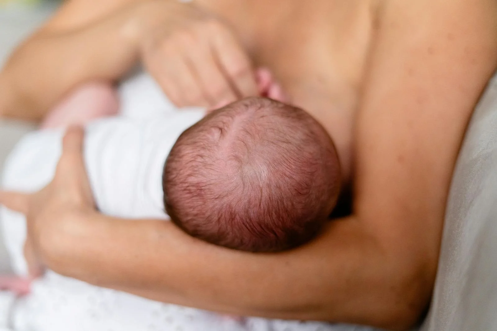 Head of Newborn in Hands of Woman While Breastfeeding.jpg