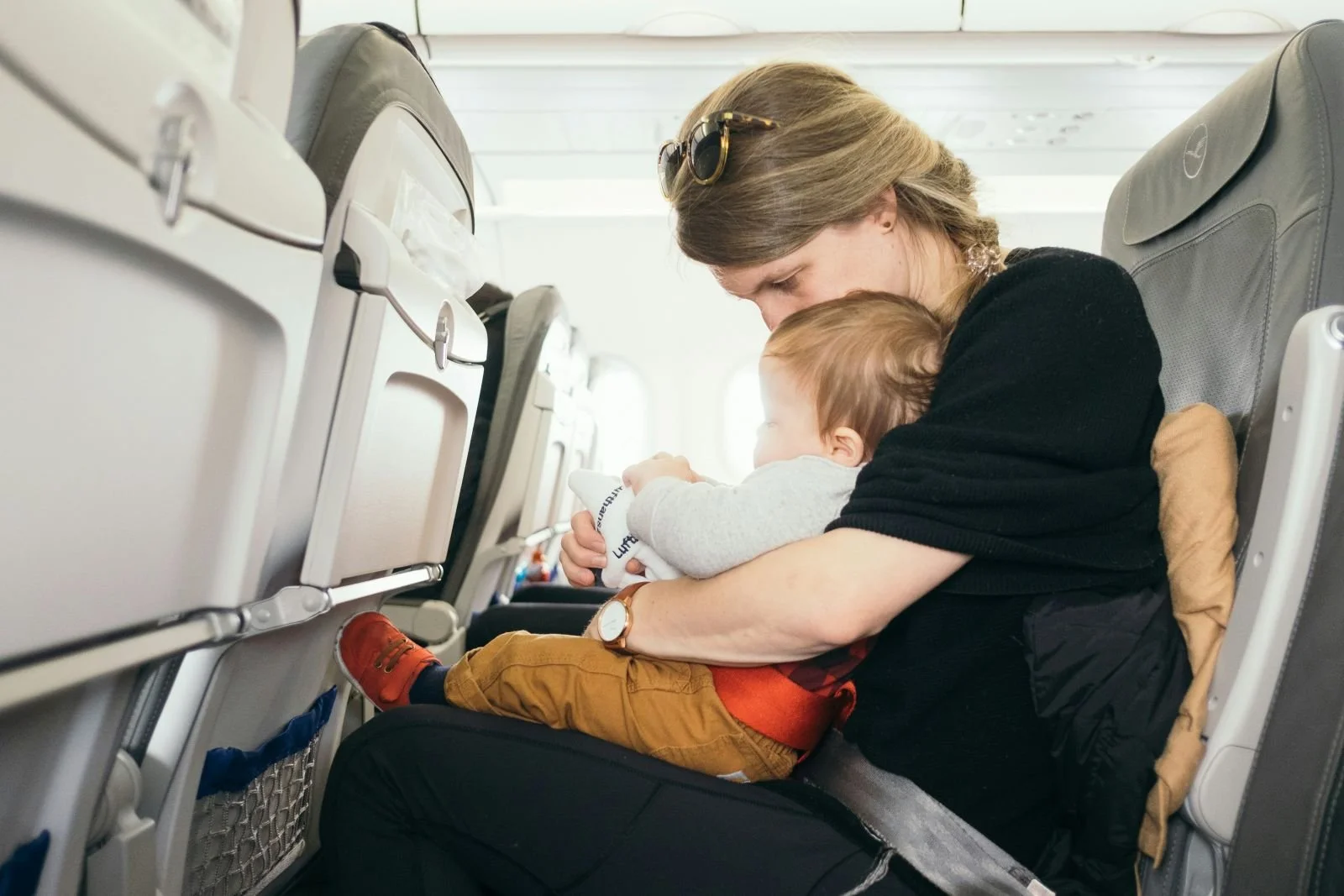 Mother holding baby on airplane during flight while travelling