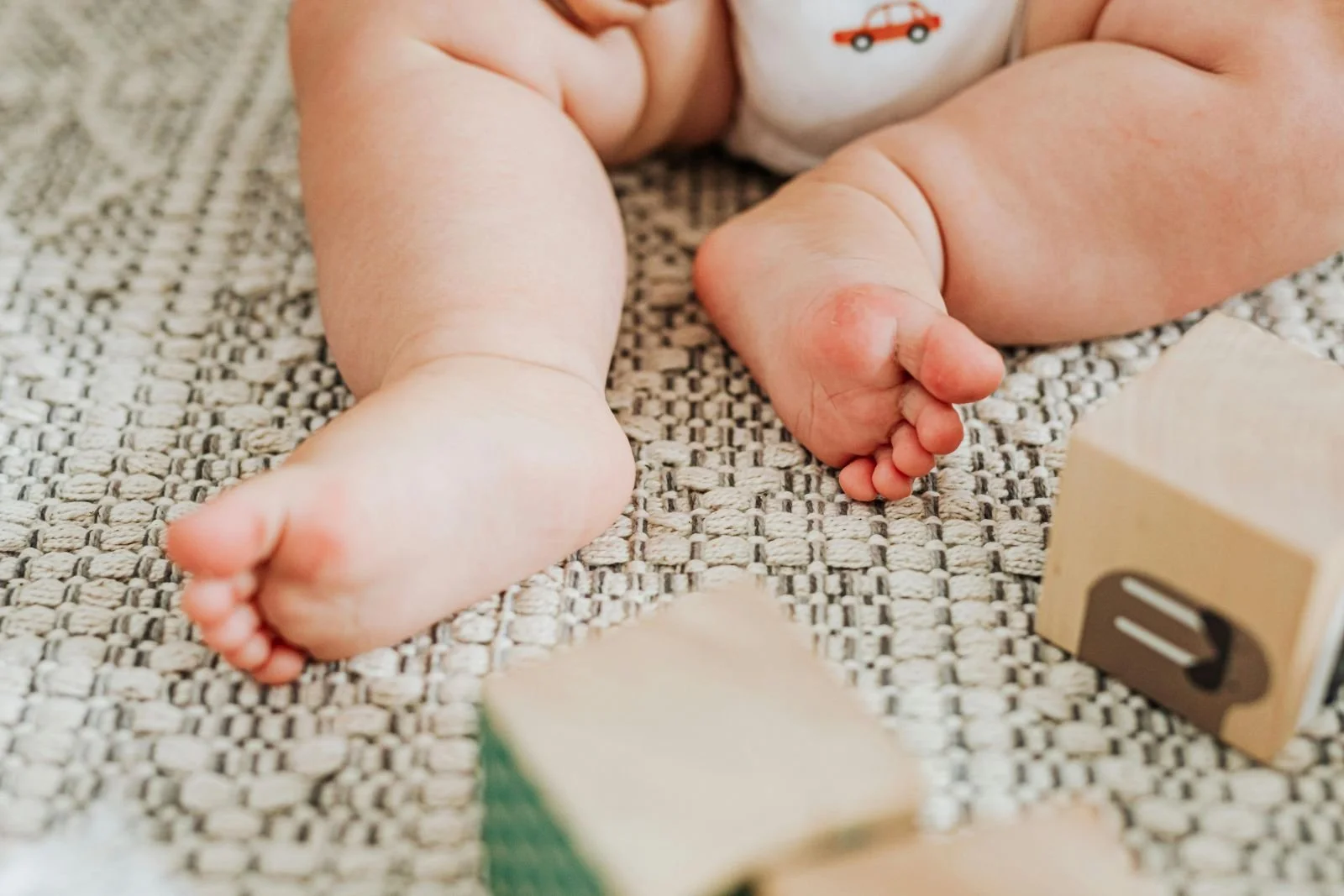 Close-up of Babys Little Feet and Wooden Building Blocks