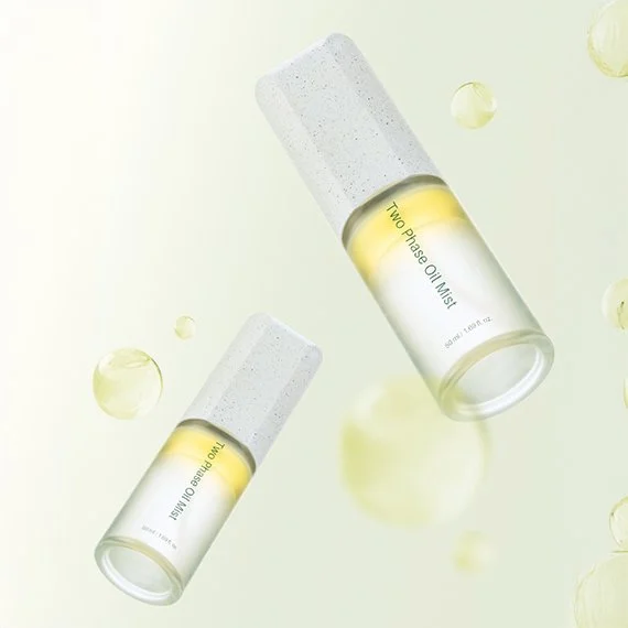 Two bottles of two-phase oil mist skincare product floating with small yellowish bubbles against a light background.