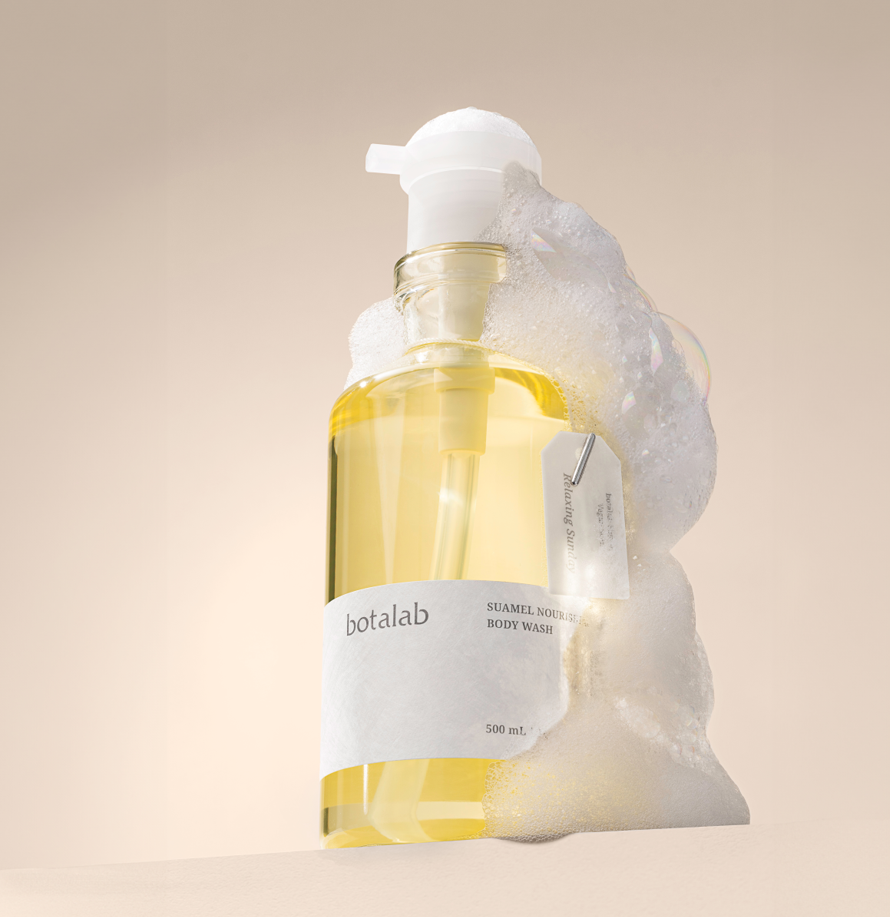 A clear plastic bottle with a pump dispenser labeled "botalab" and "SUAMEL NOURISH BODY WASH" filled with yellow liquid, surrounded by soap suds, placed against a neutral background.RIMAN Skincare | Incellderm Australia | Korean Skincare