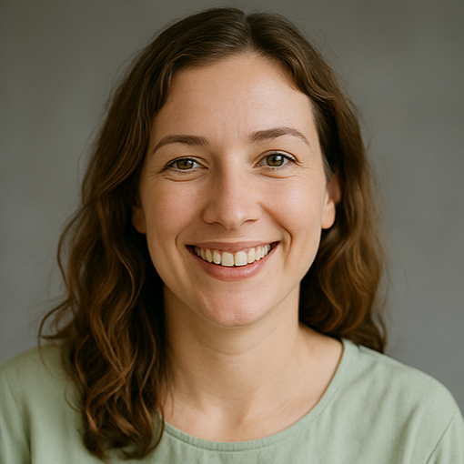 Close-up of a woman with wavy brown hair, smiling, wearing a light green shirt, against a gray background.